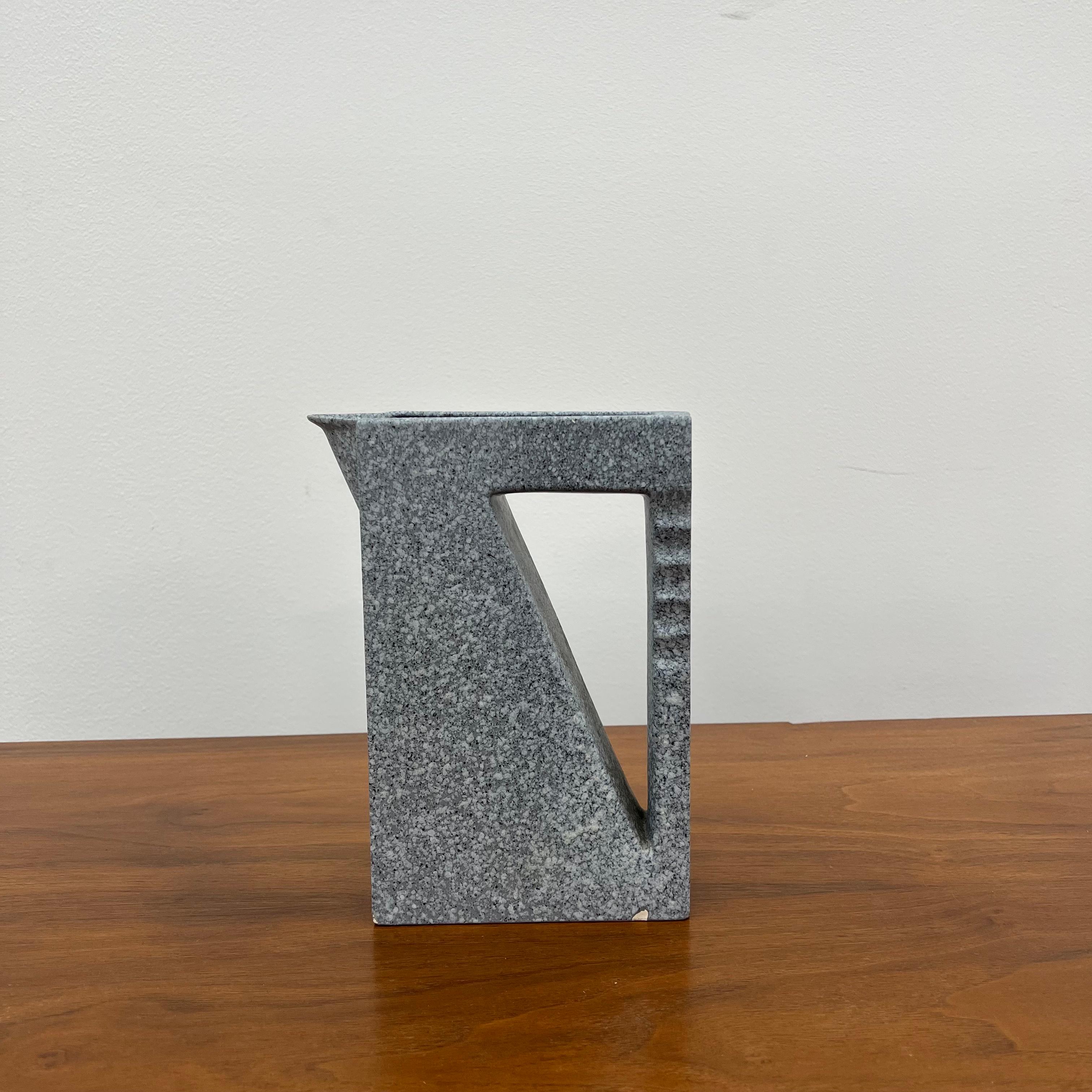 Ce pichet postmoderne a été conçu par le designer français Claude Dumas en 1986. Cette céramique est finie dans une glaçure grise mouchetée.
 