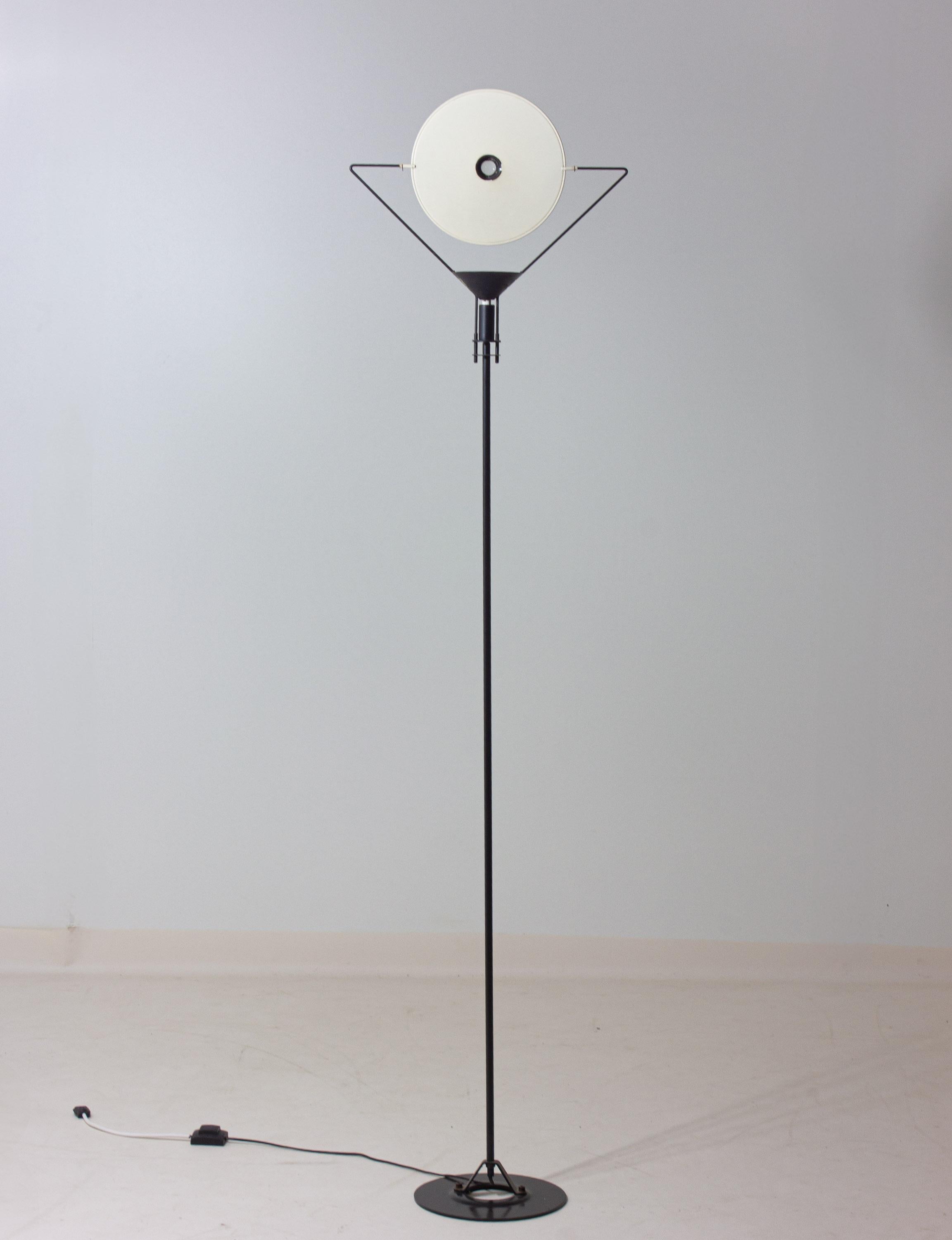 Se trata de una lámpara de pie Polifemo diseñada por Carlo Forcolini para Artemide en la década de 1980.
Tiene un armazón de metal negro con un delgado vástago vertical, una base circular y un zócalo en forma de cono que soporta un reflector de