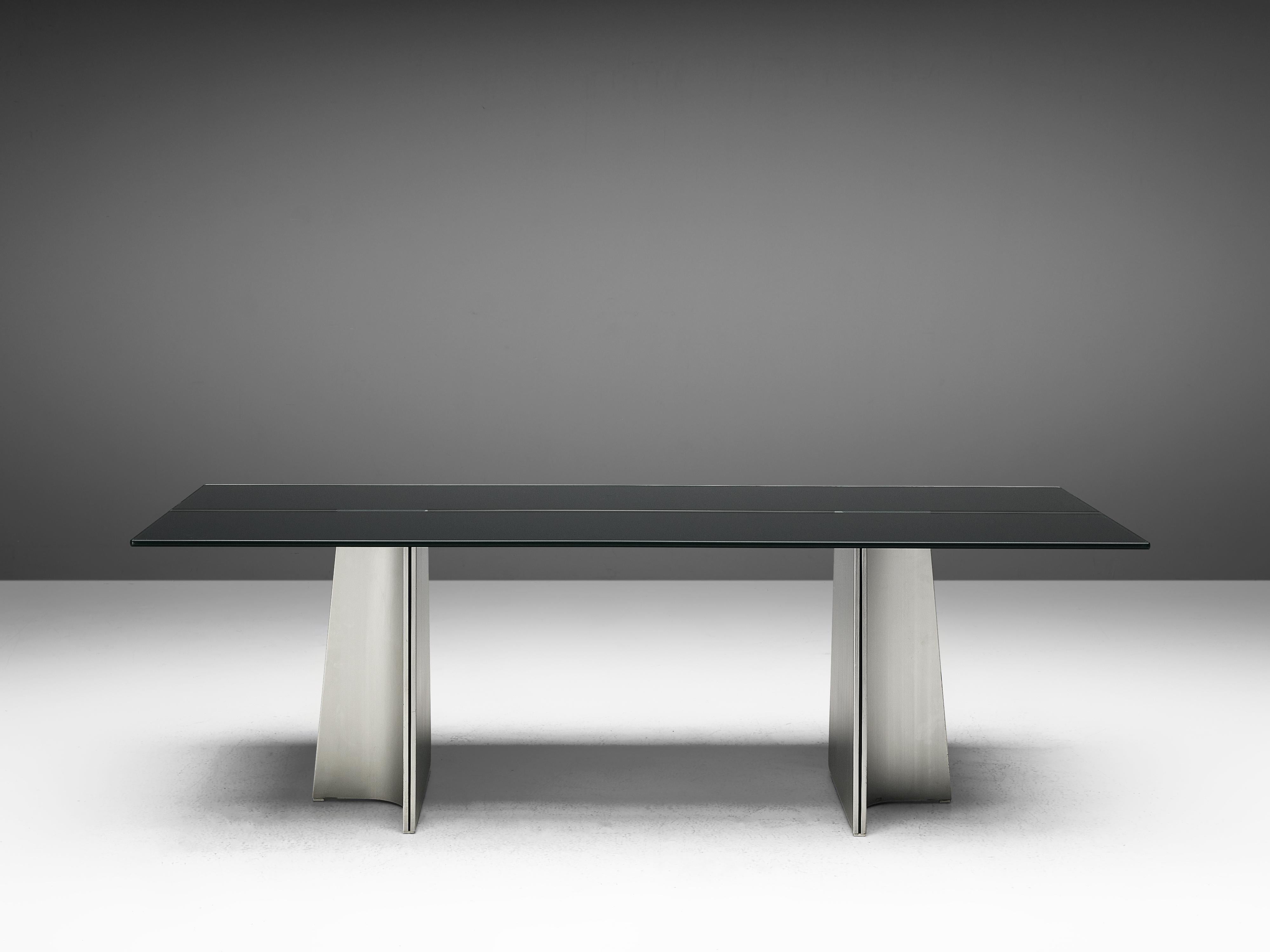 Luigi Saccardo, dining table model 'Ufo', metal and glass, Italy, 1970s.

What makes the ‘Ufo’ dining table so expressive is the way two sculptural metal legs lift up the darkened tabletop. The legs consist of a triangle-shaped form that has two