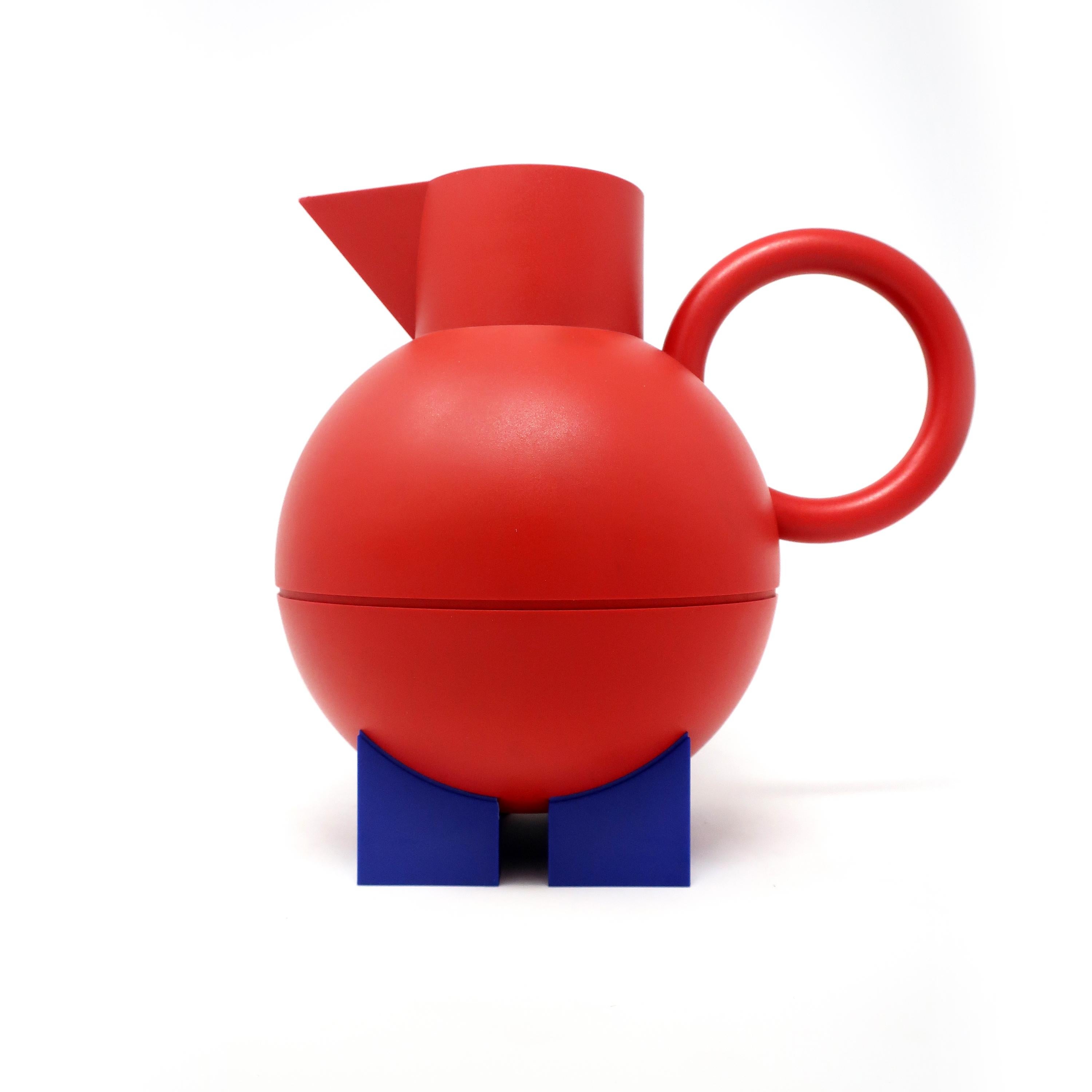 A classic design by Memphis Milano-affiliated American postmodern designer and architect Michael Graves for his Euclid line for Alessi, the Italian home goods powerhouse. A red handle, triangular spout, and rounded body sitting on blue rectangular
