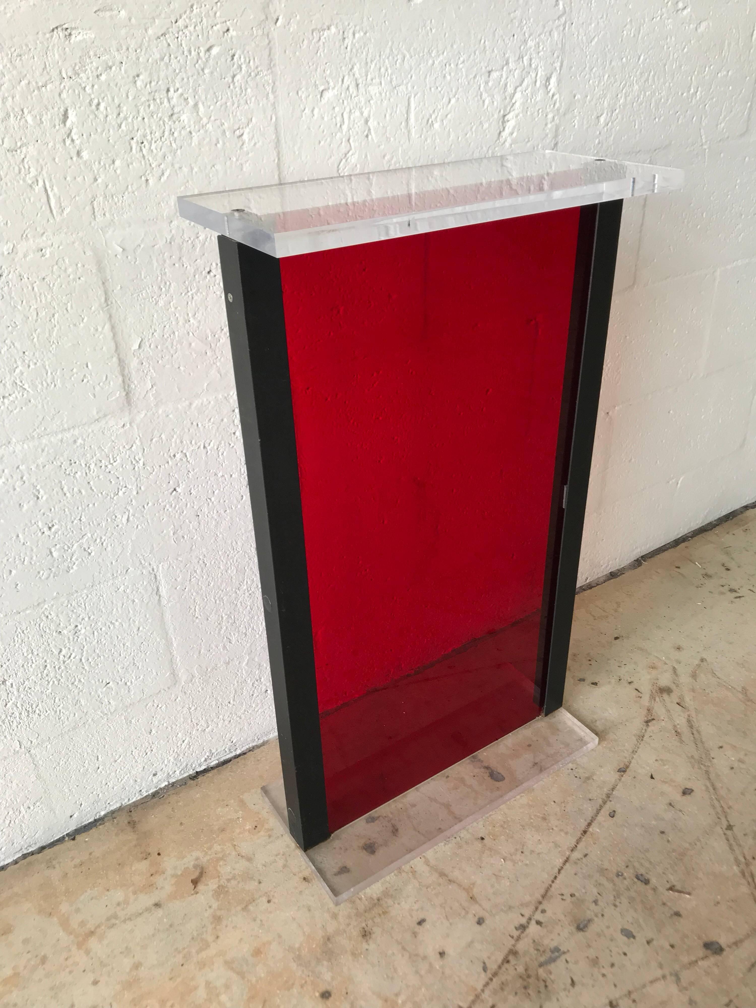 Postmodern display pedestal rendered in red and clear Lucite with a black steel frame, from the original Versace store in Miami Beach