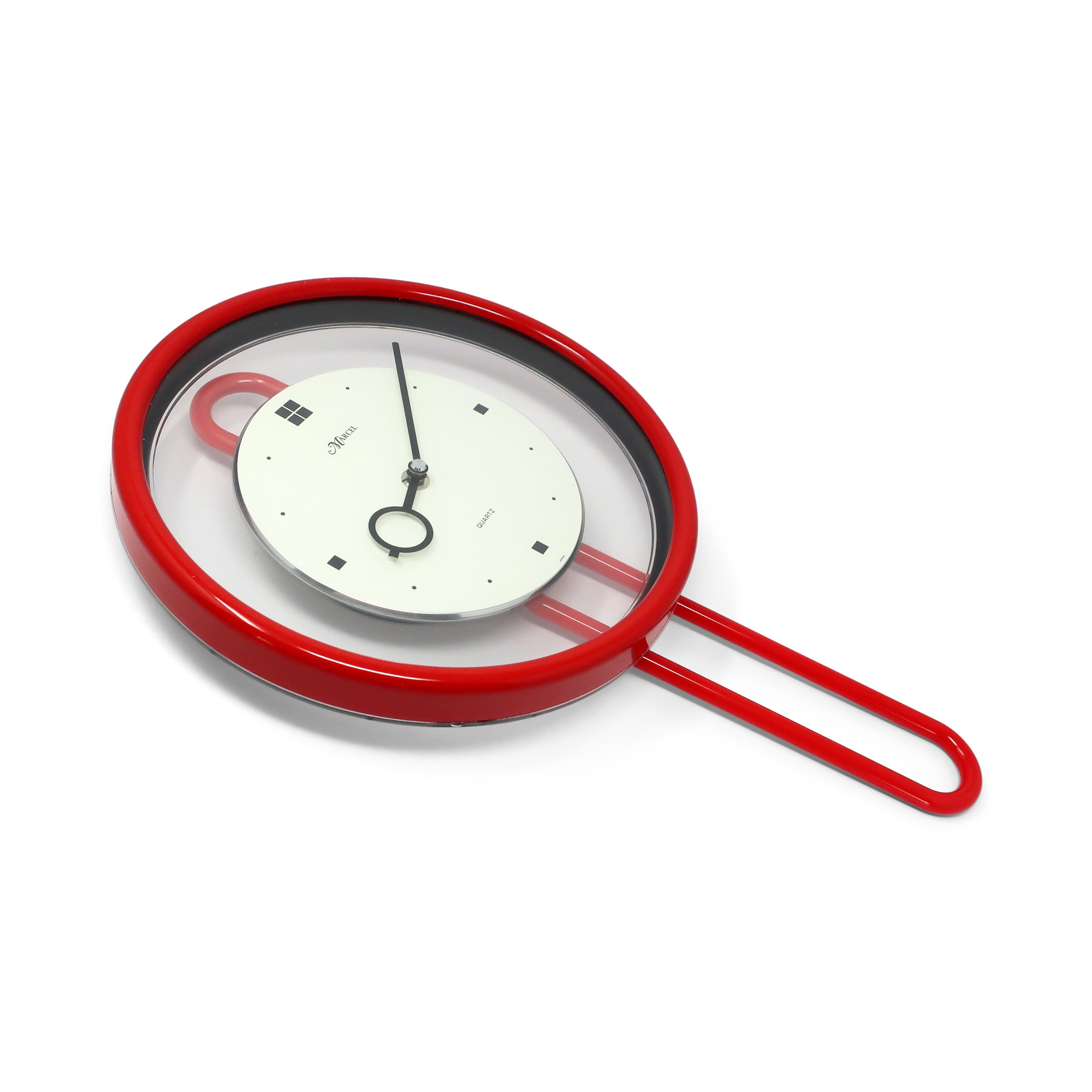A postmodern pendulum wall clock by Marcel, likely from the 1980s, with a red plastic case and pendulum, clear lucite and white face, black hands, and black numbers. With perfectly contrasting colors and a gentle swaying pendulum, this clock