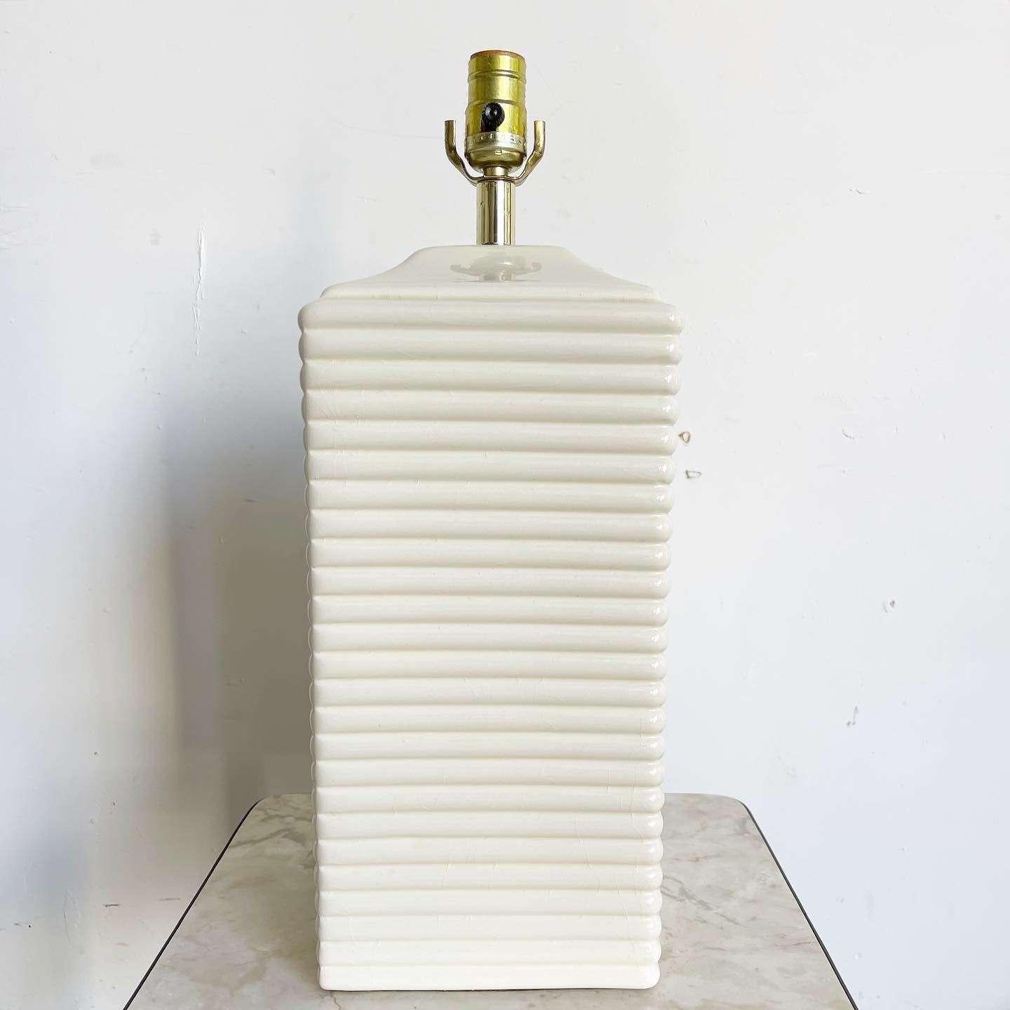 Introduce a touch of timeless elegance to your space with this incredible vintage postmodern ribbed column table lamp. Crafted with a glossy cream finish and adorned with a ribbed build, this lamp exudes a sophisticated charm that complements any