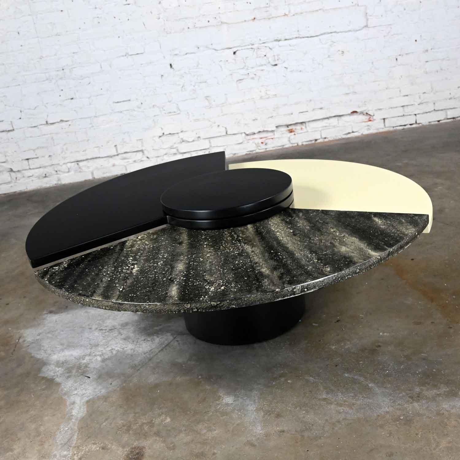 Awesome postmodern rotating coffee table comprised of a black cylinder base hosting three rotating wedges one black, one off white, & one faux marble finished lacquered MDF or Medium Density Fiberboard after Dakota Jackson’s Self Winding Coffee