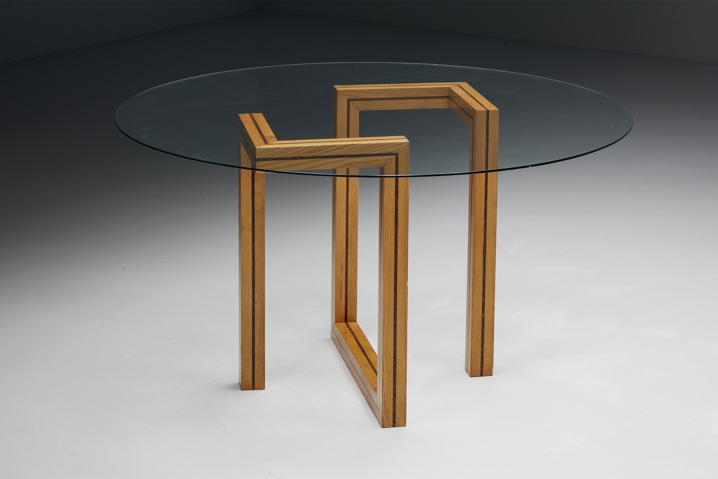 Postmodern; round; glass; dining table; geometric base; wood; working desk; architectural; post-modern; 

The legs of this postmodern dining table are based on a well-thought-out wooden structure. This wooden frame holds the round glass tabletop