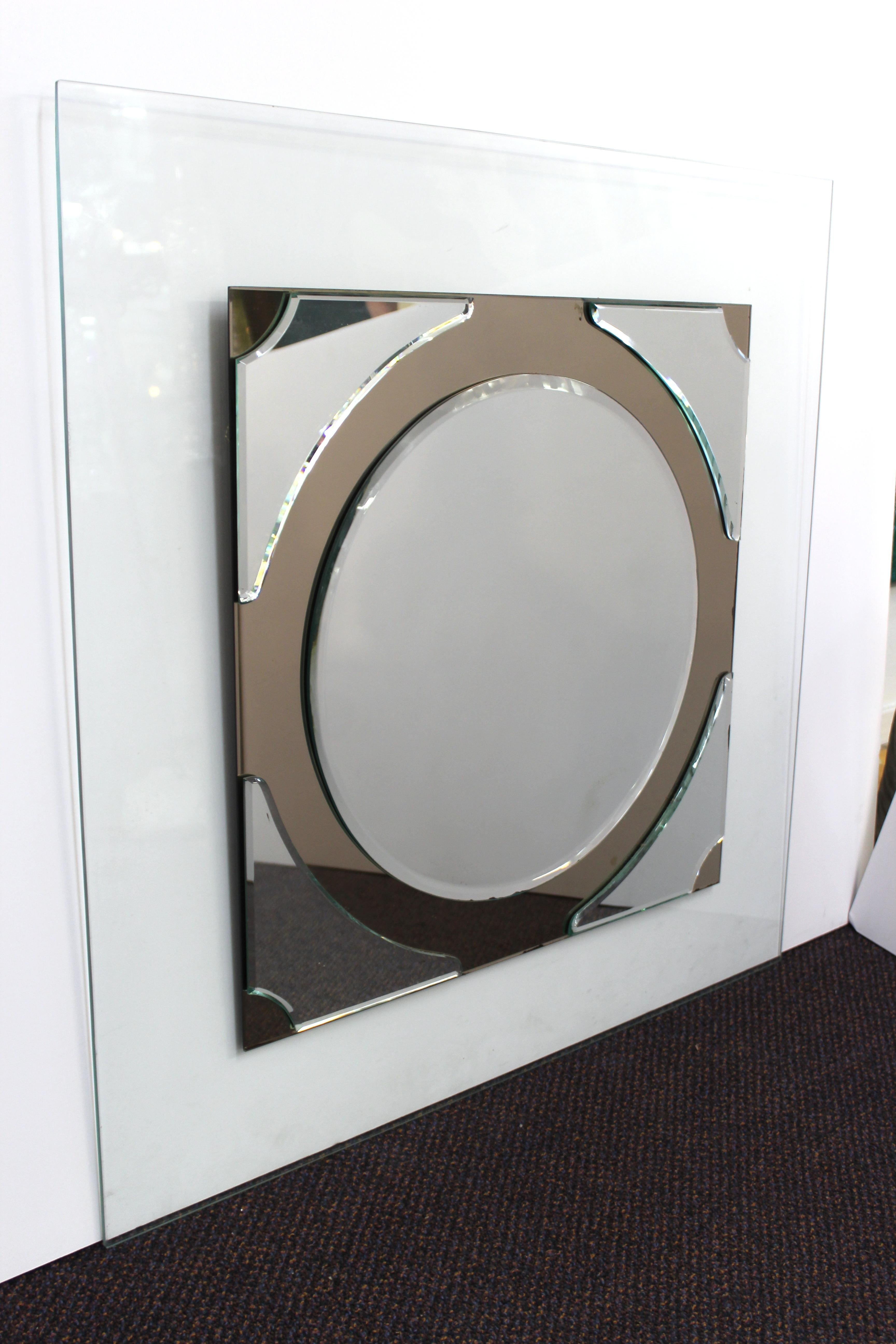Postmodern wall mirror consisting of a round mirror with edge corner mirror elements, bedded atop a rectangular glass surface. The piece dates from the circa 1990s and is in great vintage condition.