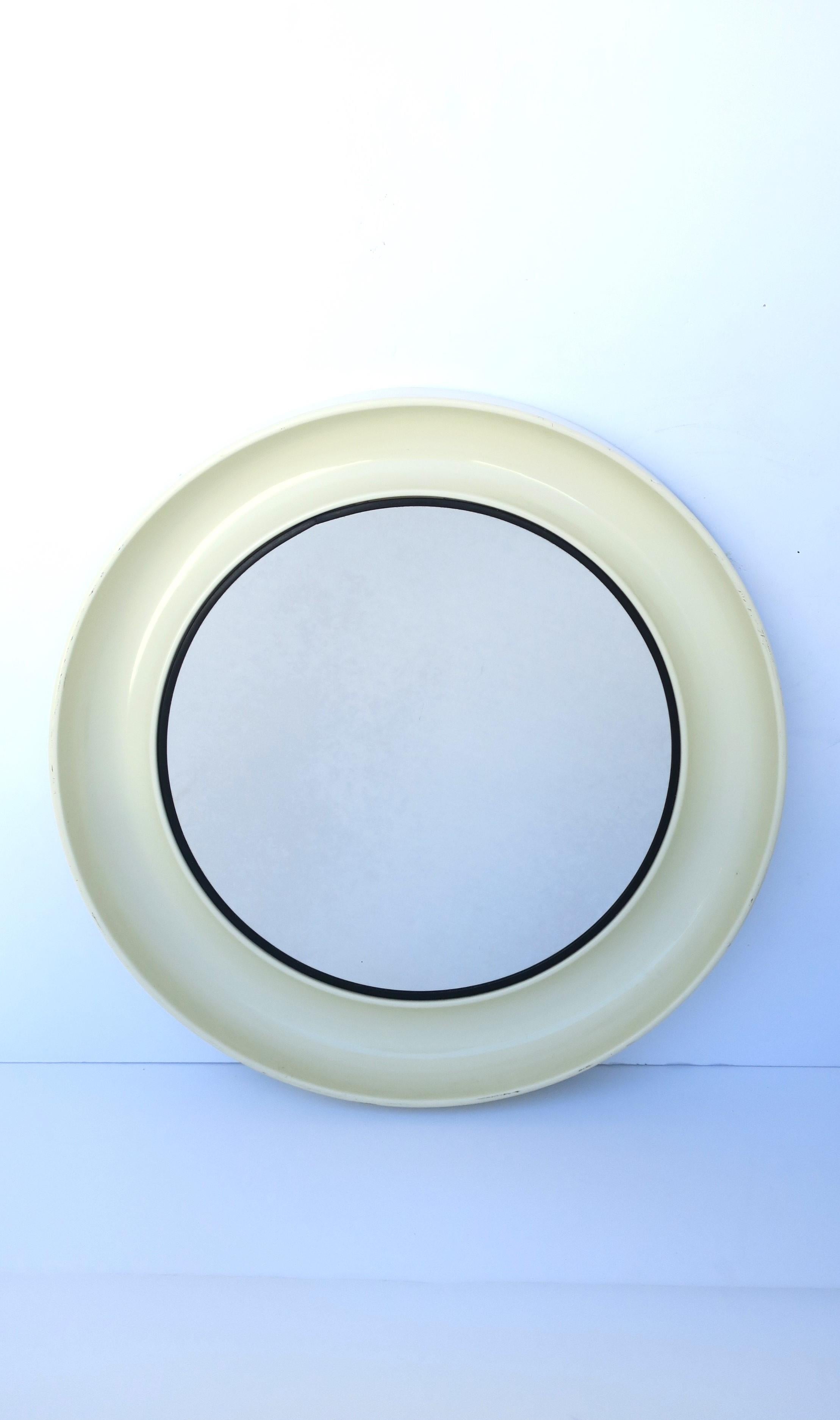 A chic Post-Modern Scandinavian Danish off-white cream and black round wall mirror, circa late-20th century, Denmark. Mirror's frame is an off-white cream hue with black accent around glass mirror. Mirror's frame is a plastic material with a concave