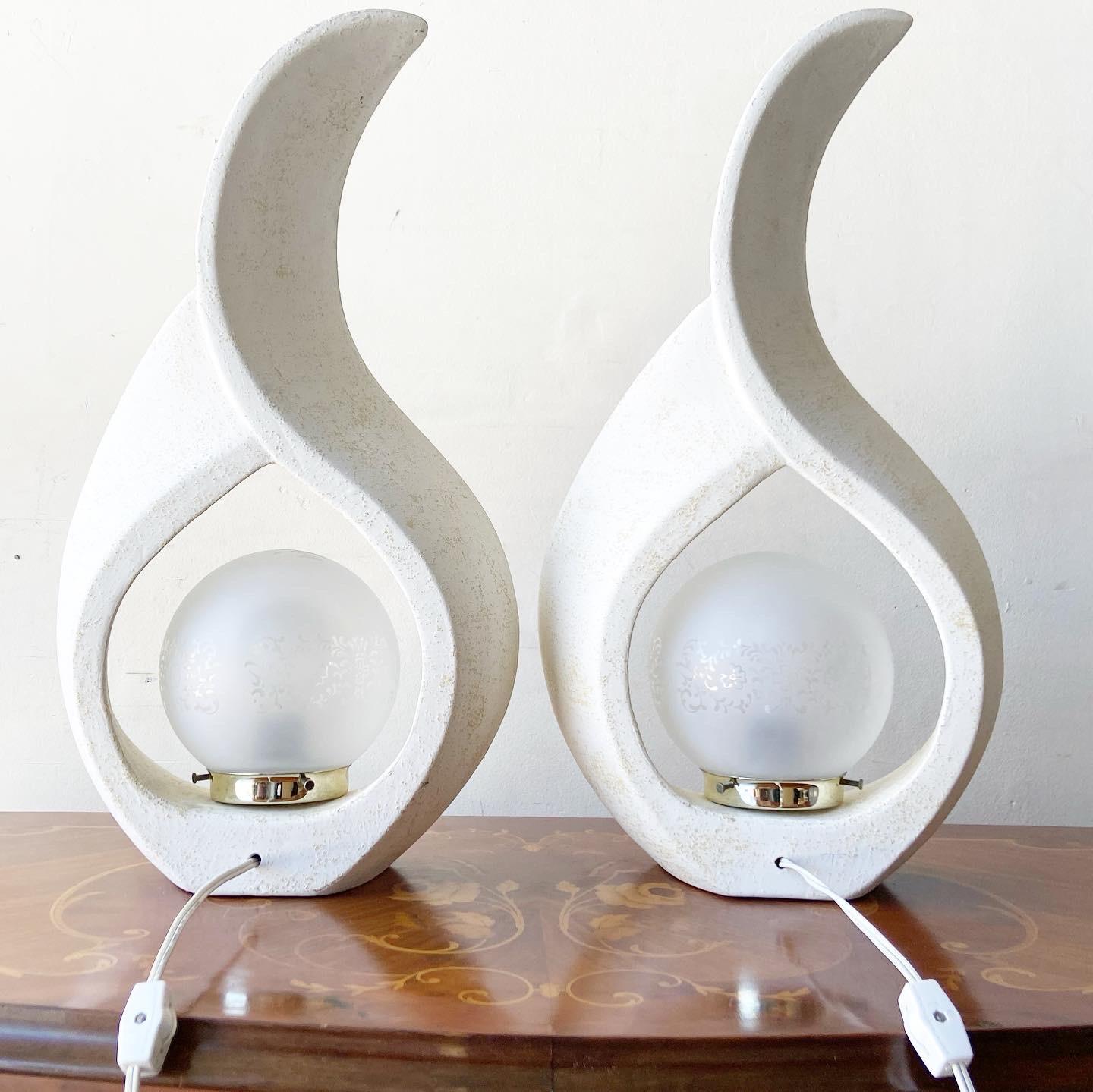Incredible pair of postmodern sculptural flame lamps. Each feature a distressed white over the rough ceramic texture. The frosted glass spherical lamp shade displays an etched floral pattern.