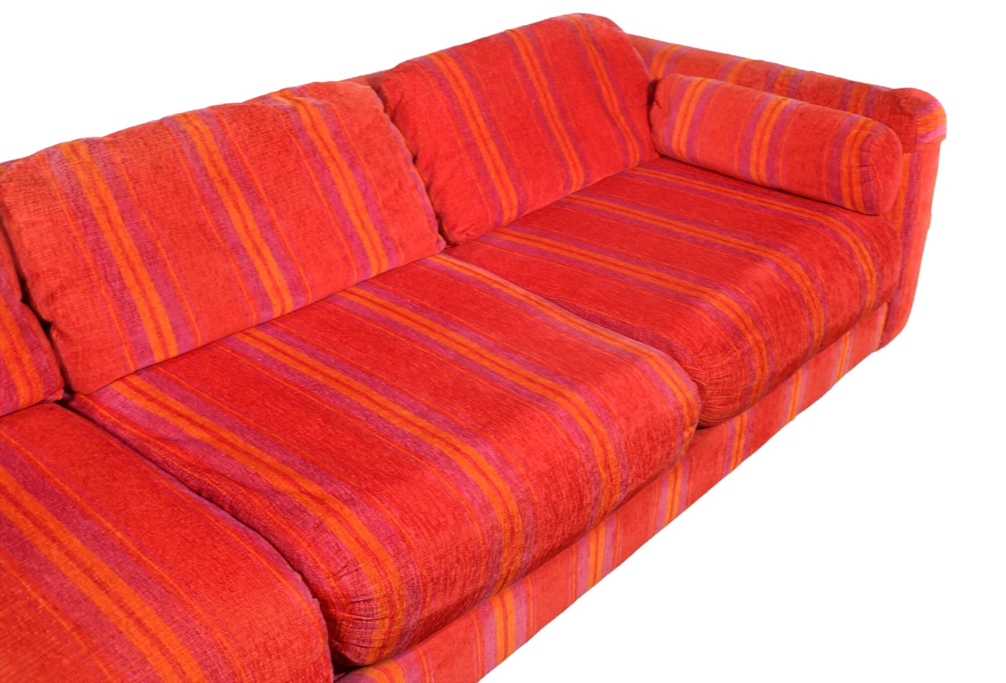 Chic 1970’s box sofa by Selig having polychrome stripped fabric upholstery, probably by Jack Lenor Larsen, on cylindrical chrome legs. Comfortable to sit, lounge, or even lay down on, this well crafted piece exhibits the casual modernist style