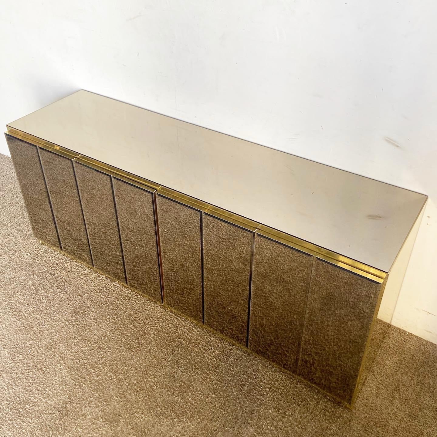 Elevate your decor with the Postmodern Gold Mirror Credenza. This luxurious credenza combines smoked beveled mirror panels with gold accents, blending functionality with a touch of opulence.
One chip on the bottom corner of the mirror door as seen