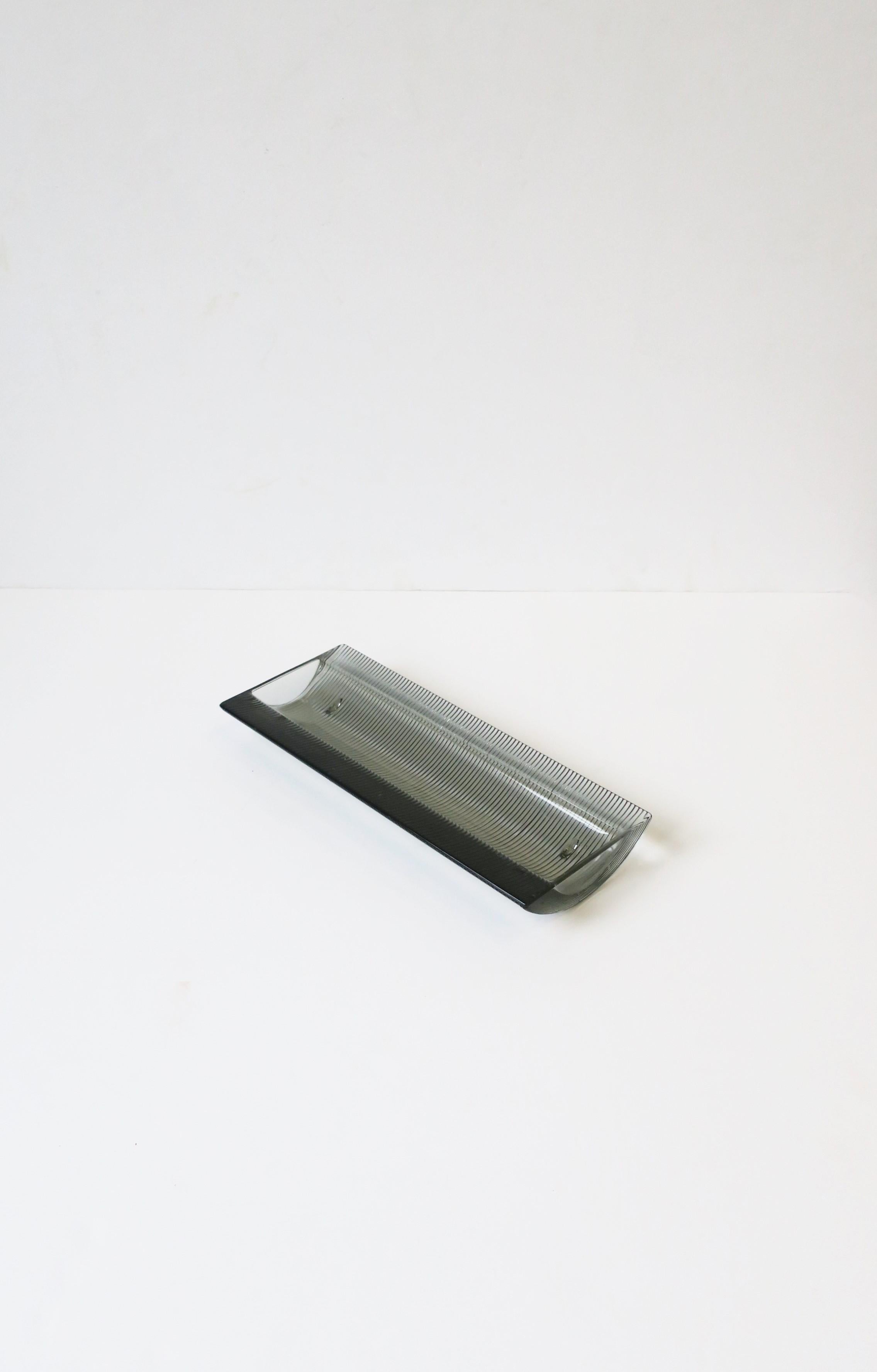 A Postmodern dark grey hue smoked glass desk catchall vide-poche, circa late-20th century, Europe. Piece is oblong, with a fluted base and small feet. A great piece for a desk to hold pens, letter opener, etc. or on a vanity, dresser, etc. for