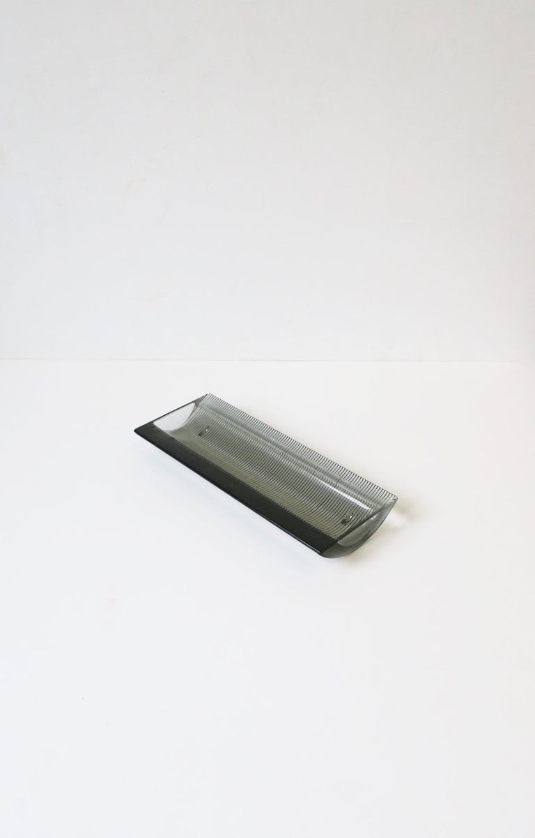 A substantial Postmodern black to dark grey hue smoked glass desk catchall vide-poche, circa late-20th century, Europe. Piece is oblong, with a fluted base and small feet. A great piece for a desk to hold pens, letter opener, etc. or on a vanity,