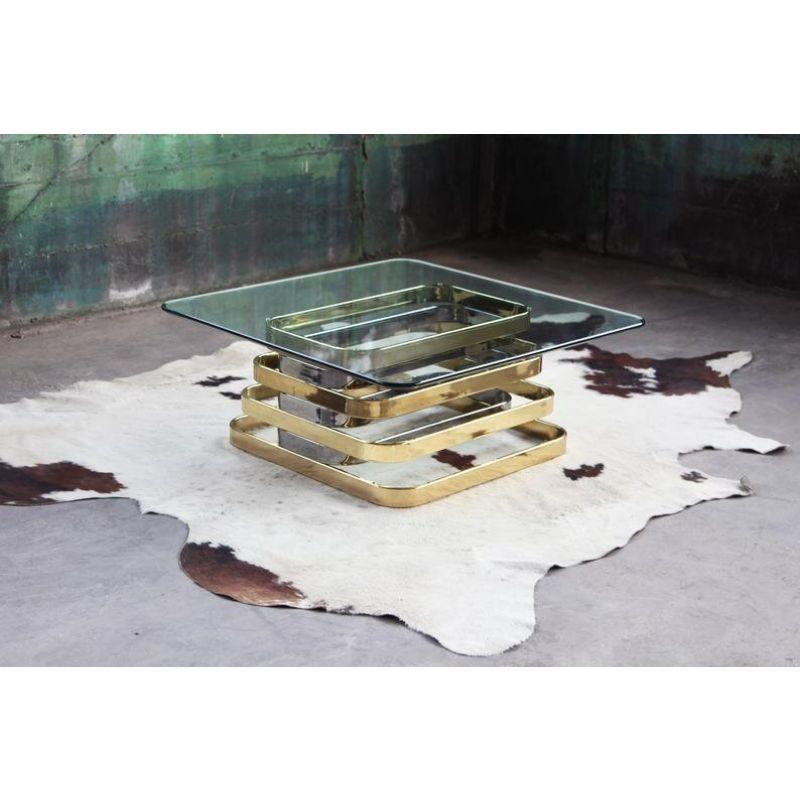 This one is a stunner!! This can be used as a Cocktail or Coffee table and features a Stacked Chrome and Brass base and a beveled glass top. The top of two striking curved rectangular surfaces swivels smoothly allowing for a various sculptural