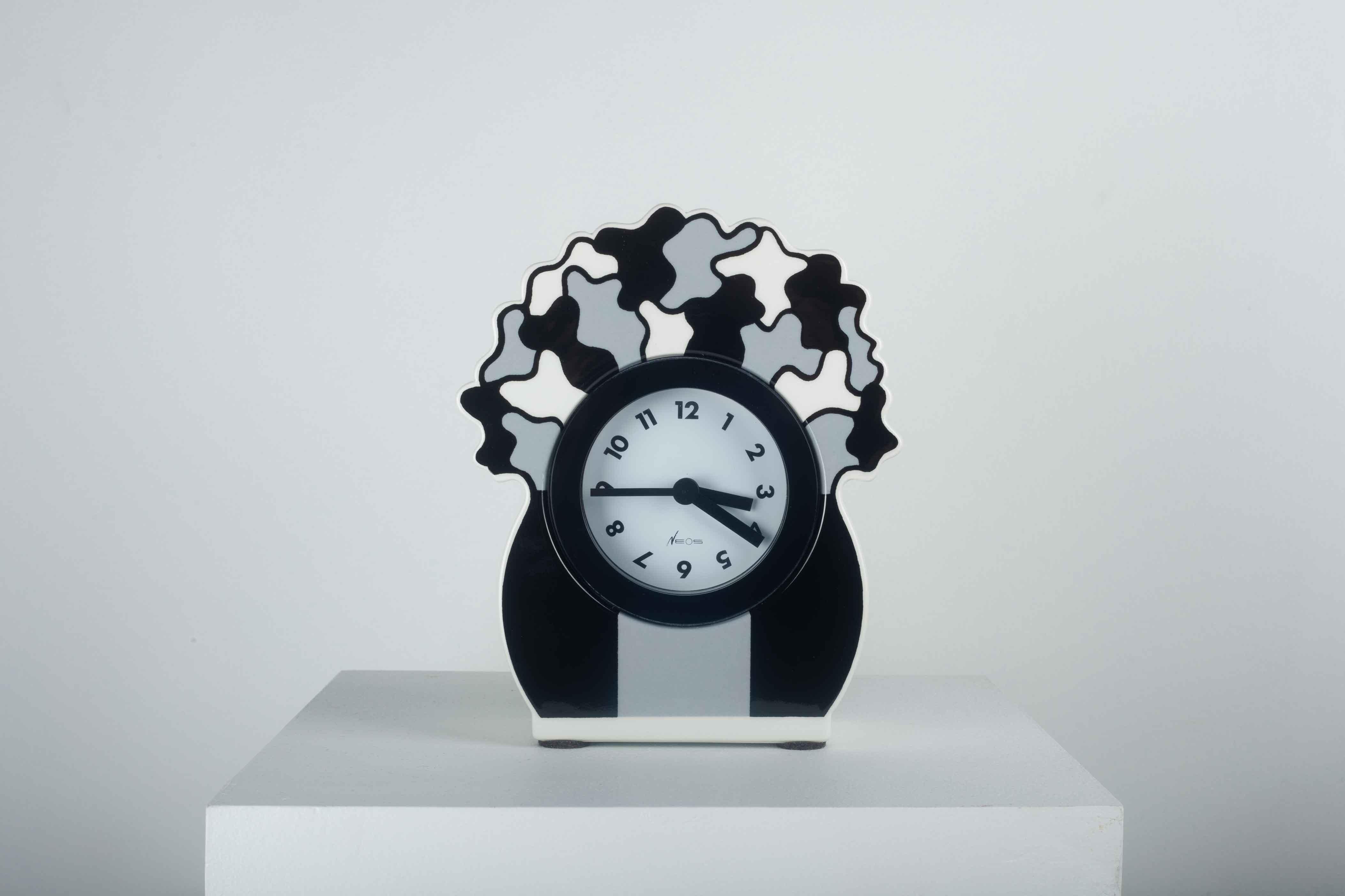 Postmodern clock for desk or table by George Sowden for Neos by Lorenz. Ceramic in grey black and white. Made in Italy in the 1980s.

Cast manufacturer's mark to reverse 'Neos of Lorenz Made In Italy Design Studio Sowden'. Sold with original