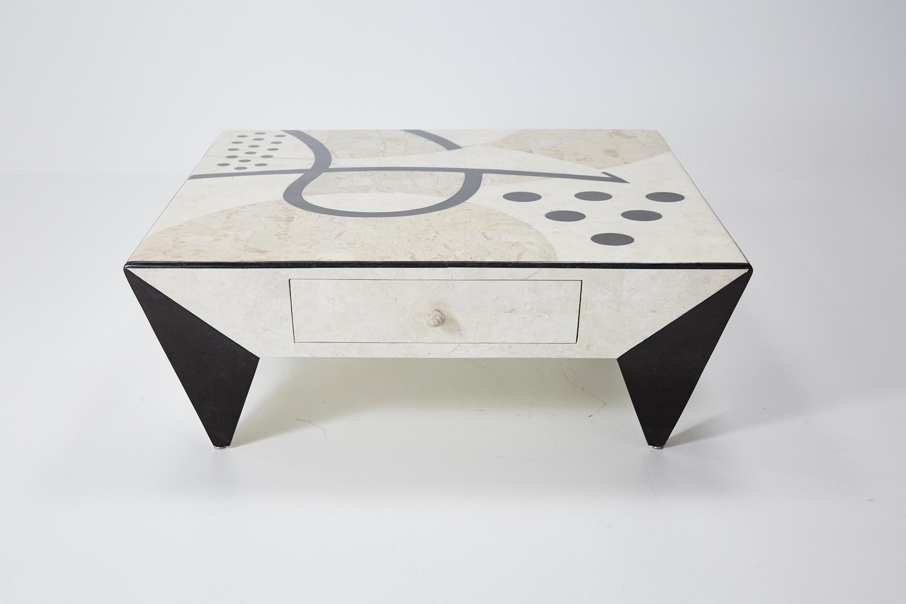 Fully covered tessellated stone square cocktail or coffee table with abstract Postmodern pattern across top in shades of white ivory, beige fossil and black inlaid stone. Stone inlaid over fiberglass body. Two sides of tabletop with drawers.

All