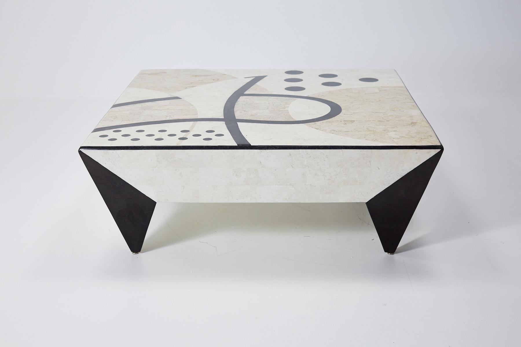 Fully covered tessellated stone square cocktail or coffee table with abstract Post Modern pattern across top in shades of white ivory, beige fossil and black inlaid stone. Stone inlaid over fiberglass body. Two sides of tabletop with drawers.