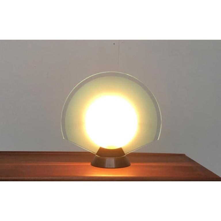 - Elegant table lamp from the Italian manufacturer Arteluce.
- The design seems to be inspired by the play of light of a solar eclipse
- The lamp has two sides with different light effects This piece has an attribution mark, European Plug (up to