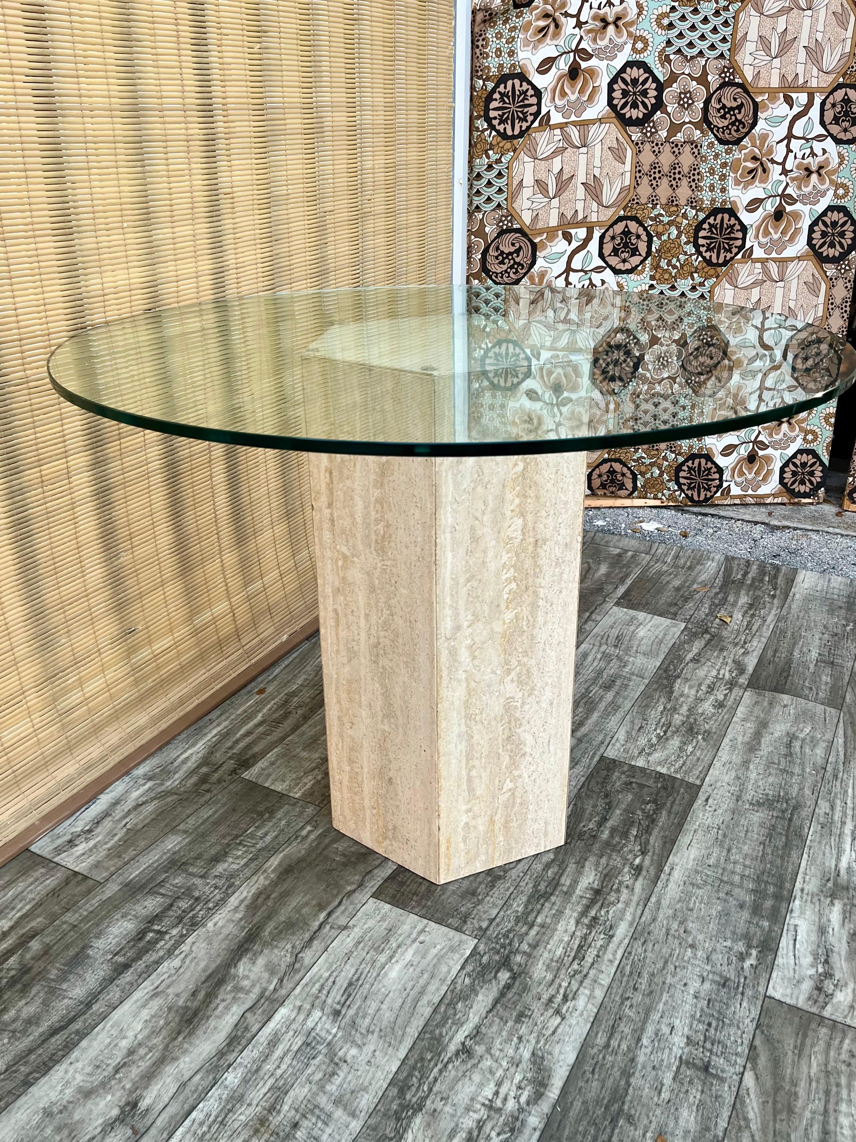 Vintage Postmodern Hexagon Travertine Pedestal Base Glass-Top Center/ Diner Table. Circa 1970s
Features a hexagon travertine base with beautiful stone veins pattern and a removable round glass top. 
Comfortable seats four guests. 
In excellent
