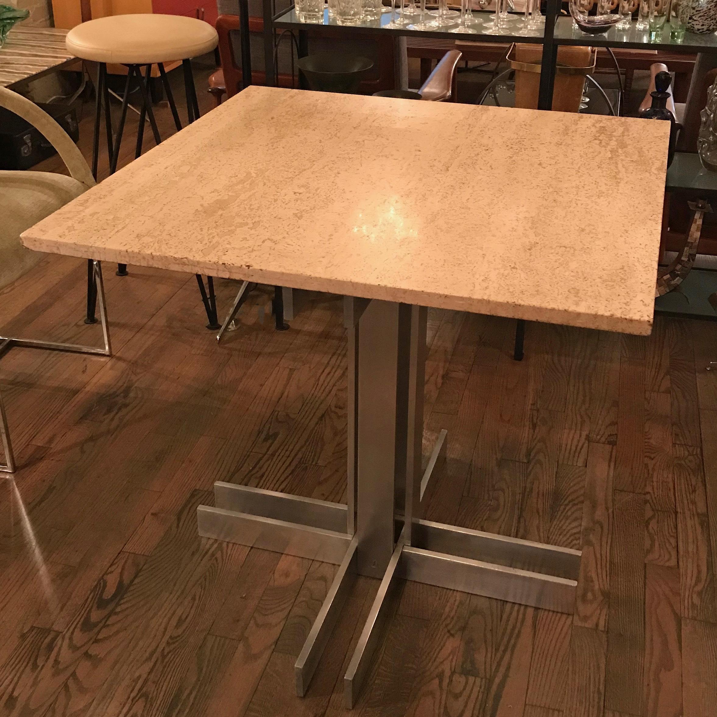 Postmodern, Memphis influenced, small dining or bistro café table features a square travertine top paired with a post-modern, architectural, machined-aluminum, pedestal base.