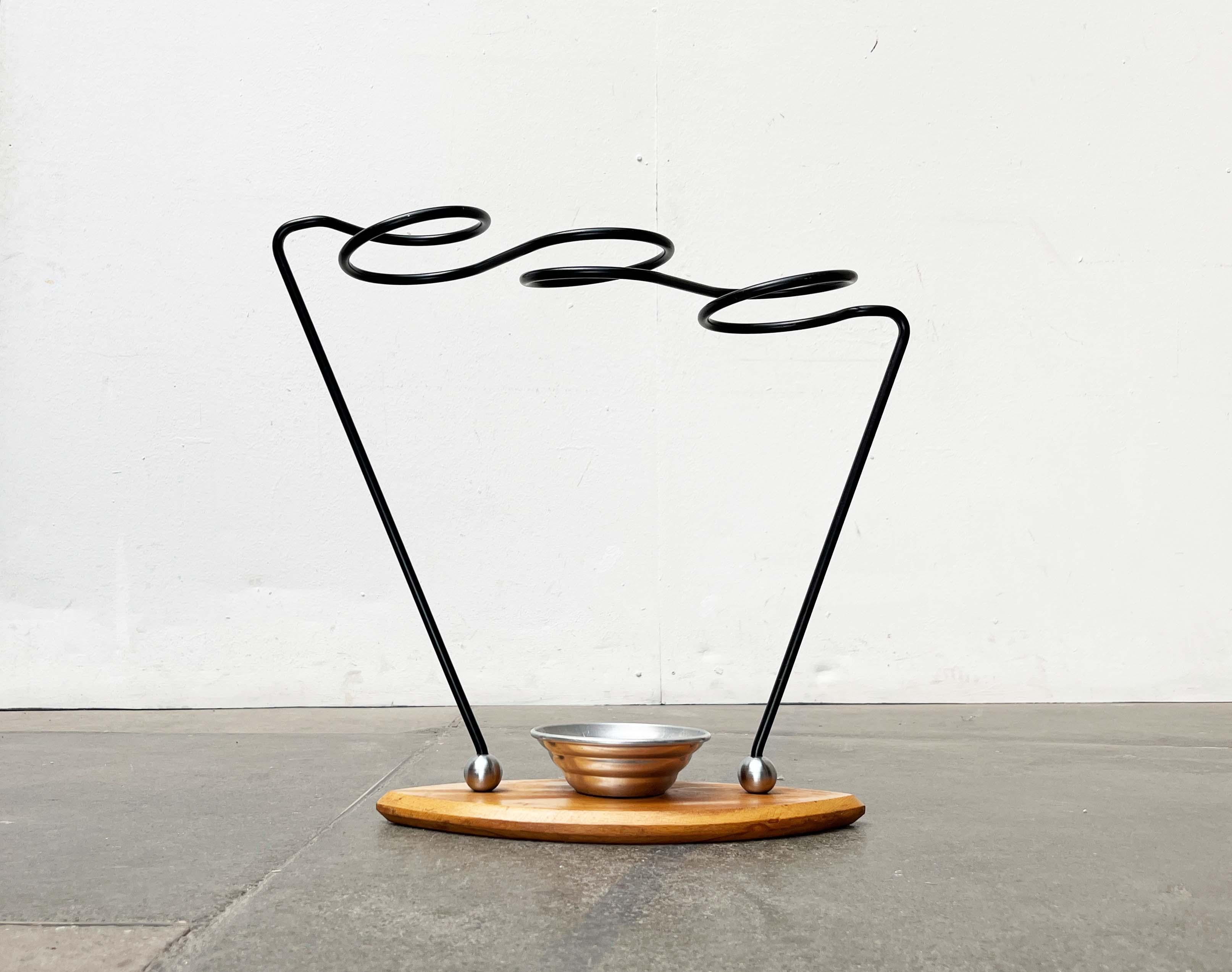 A rare umbrella stand with a postmodern design language and materiality.

A postmodern design. The material combinations and striking shapes are particularly notable. The sculpturally curved umbrella holder made of black-coated steel can be seen as