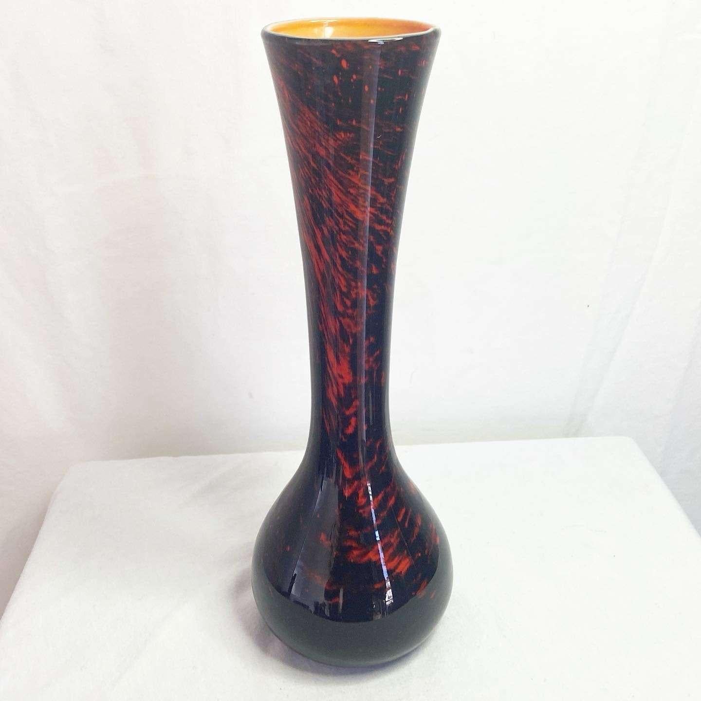 Amazing vintage glass vase. Displays a back a red glass exterior with an orange interior.
