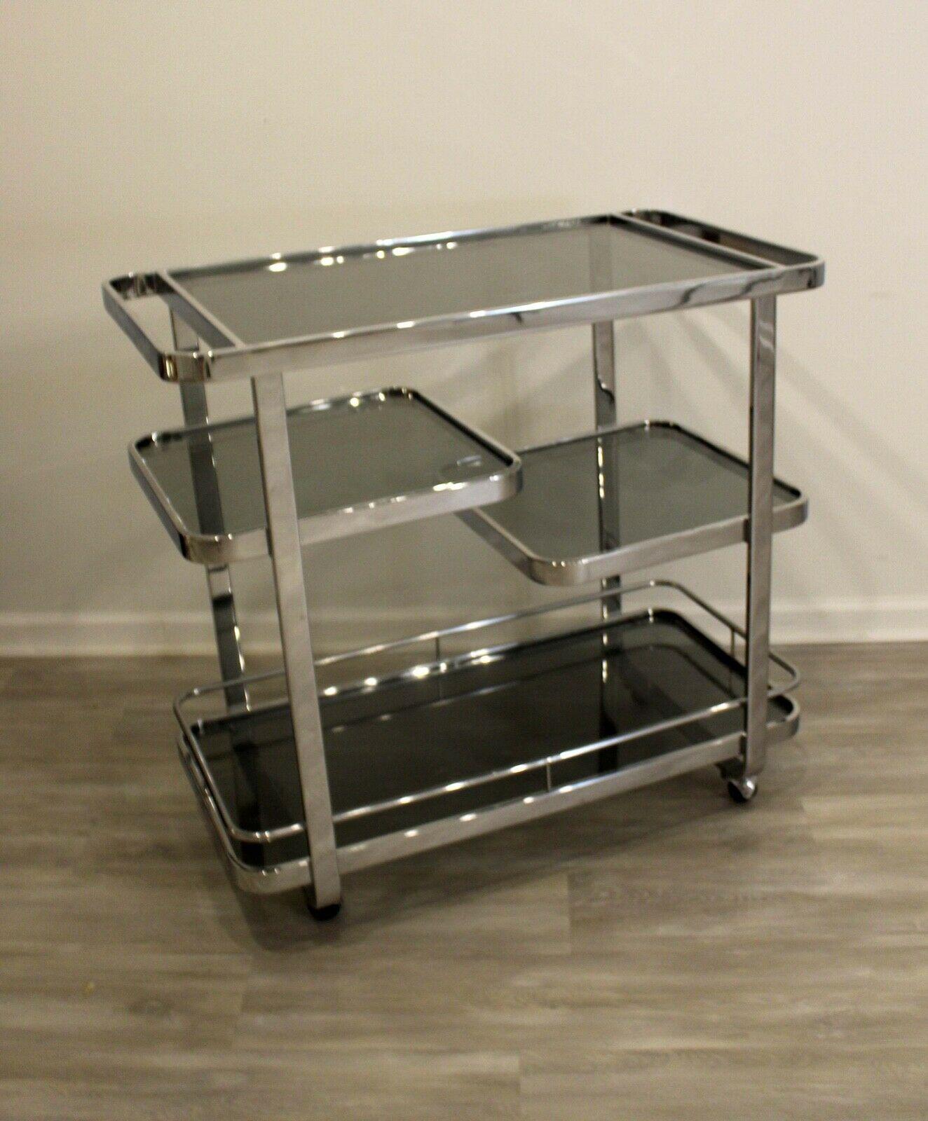 In Michigan we bring to you this polished chrome and grey smoked glass serving cart on casters. Four multi level surfaces provide ample storage for all glassware, beverages and accessories. Postmodern in style, this storage piece will work well with