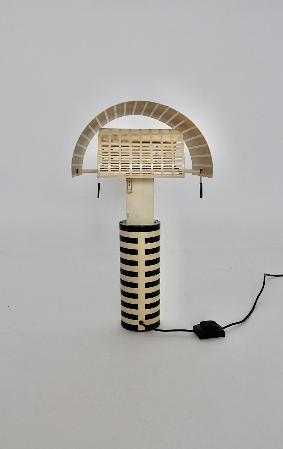 Postmodern authentic vintage table lamp from metal in black white bicolor color by Mario Botta for Artemide 1986, Italy.
An iconic and timeless table lamp with personality in black and white color stripes with two shield like lamp shades, which are