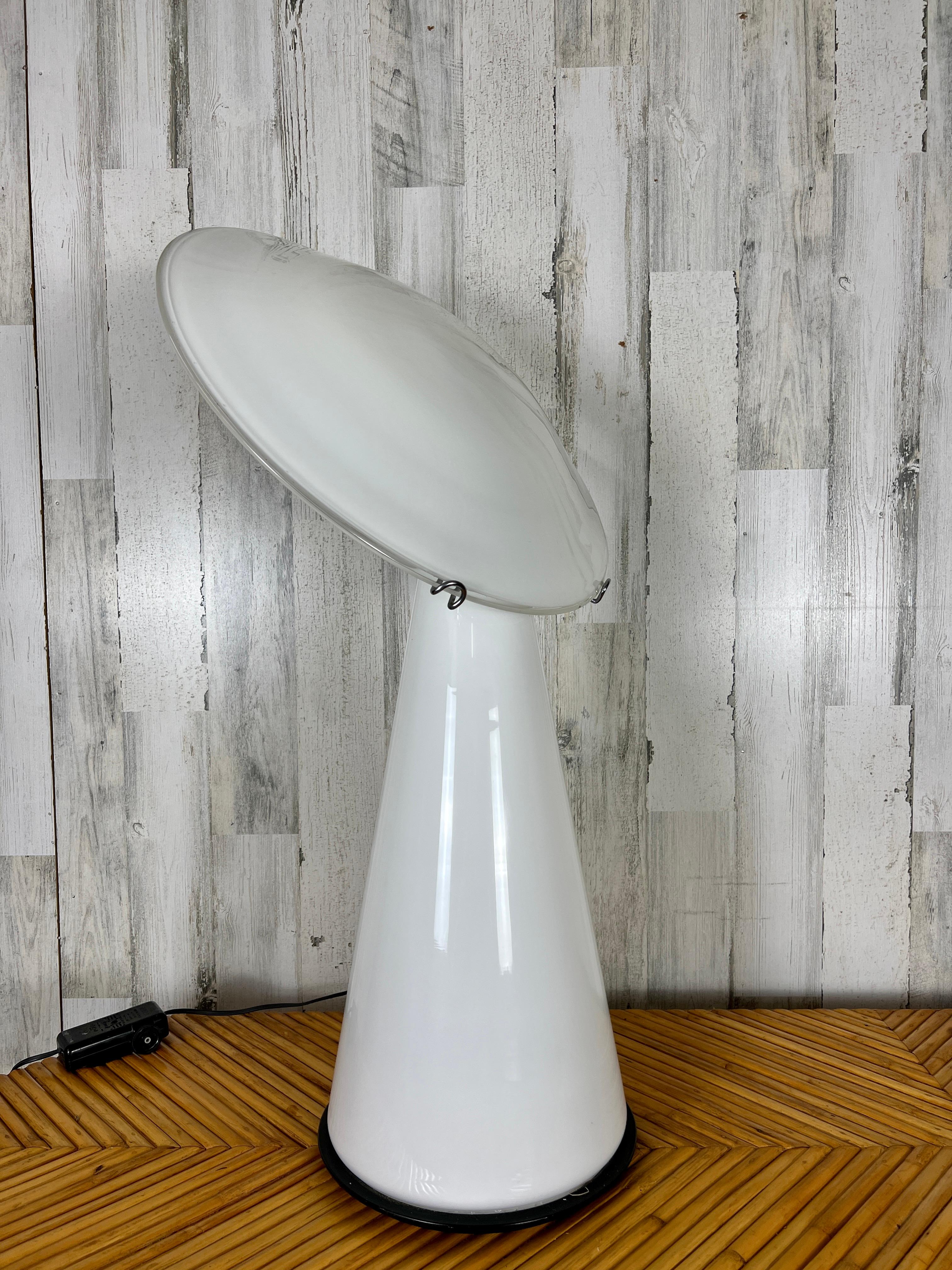 Postmodern Vistosi table lamp with slanted glass disc on a conical glass base.