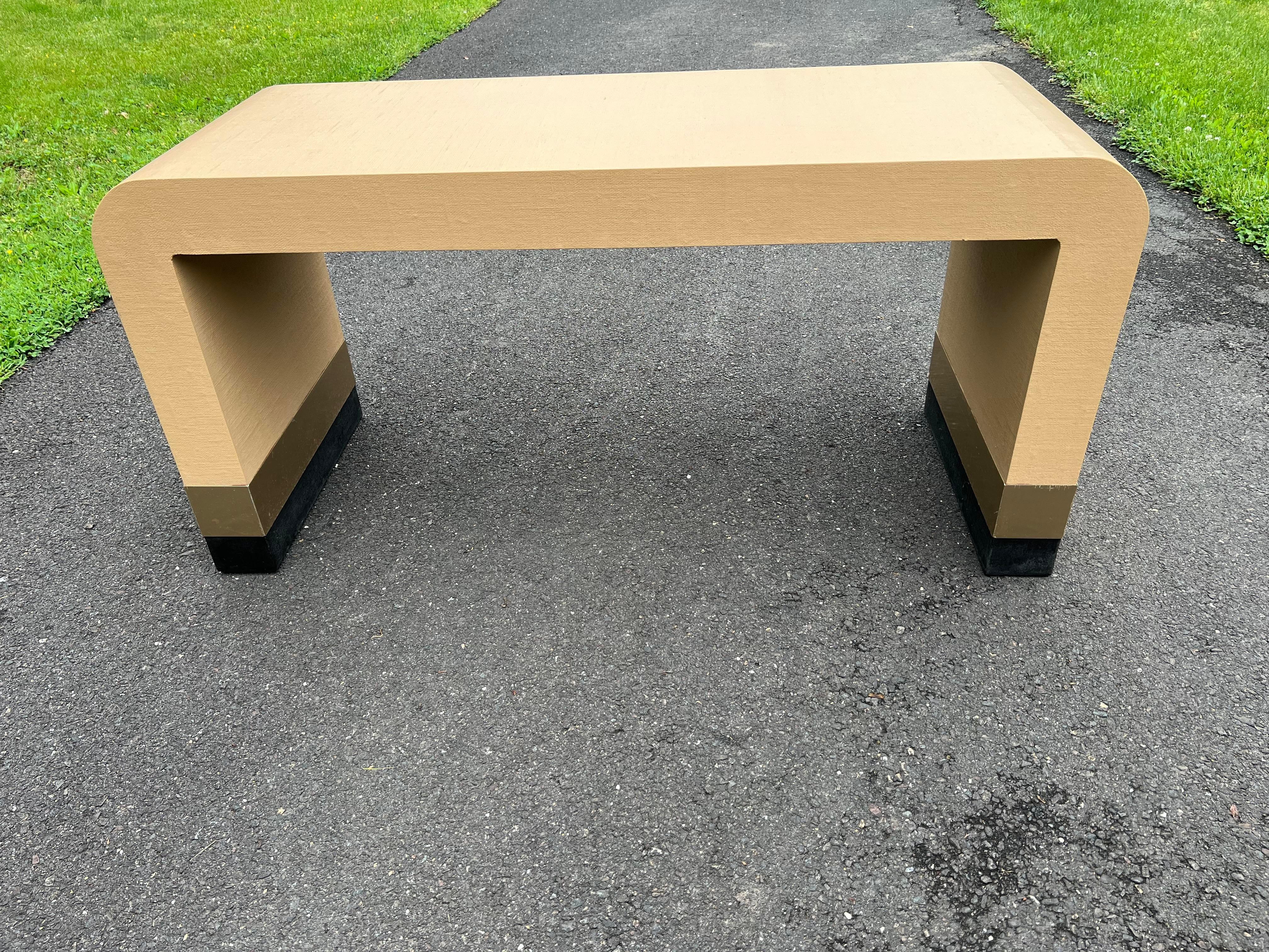 Custom made waterfall console table with linens like texture. The table was made in 1980s and the color is peach with the brass trims near the foot on both sides.