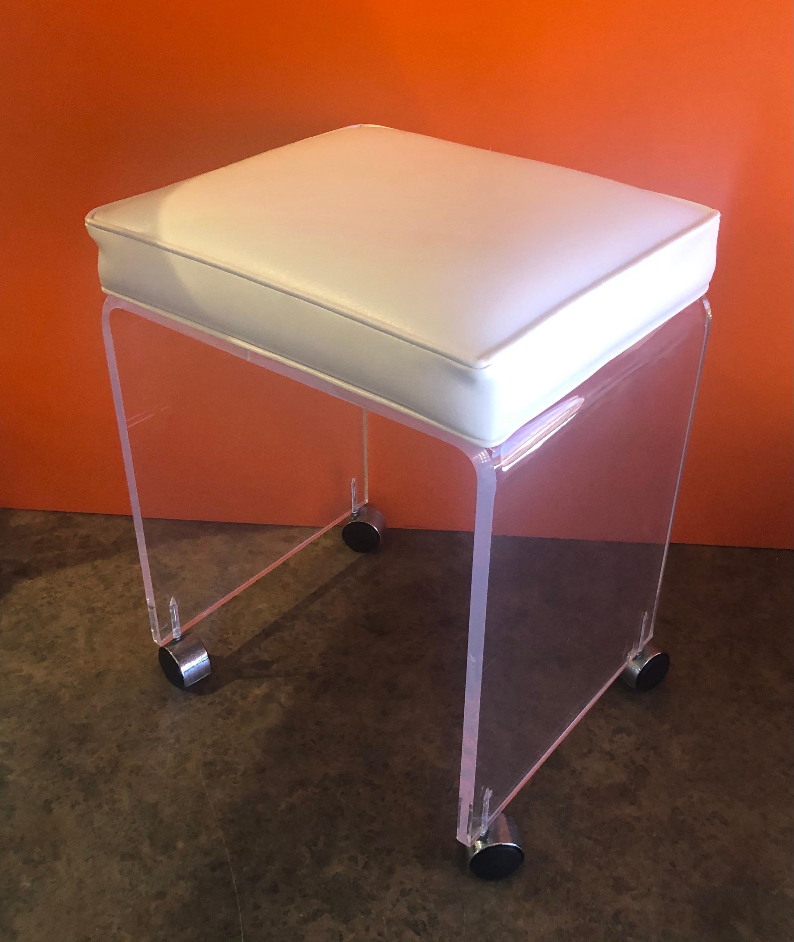 Postmodern waterfall Lucite vanity stool or bench by Akko, circa 1970s. The bench has a white colored Naugahyde seat and is in good vintage condition; very solid and stabile. There some scratches, crazing and fogging to the Lucite. #1315.