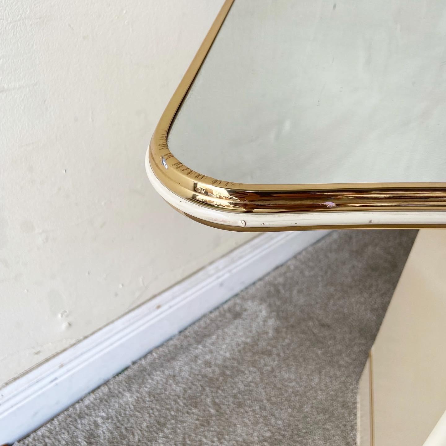 Amazing cream postmodern 1980s console table. Features a wavy mirrored top with a gold trim.
 
