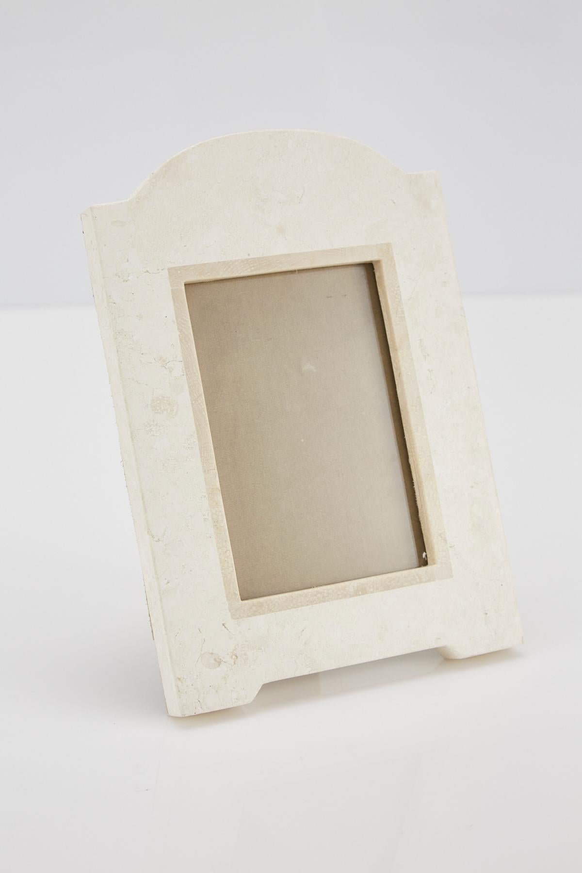 Rectangular picture frame in tessellated white stone with beige fossil stone accent and arched top. Beige felt back. Opening for picture measures 6 x 4 in., frame overall measures 10 3/4 x 7 3/8 in.

All furnishings are made from 100% natural Fossil