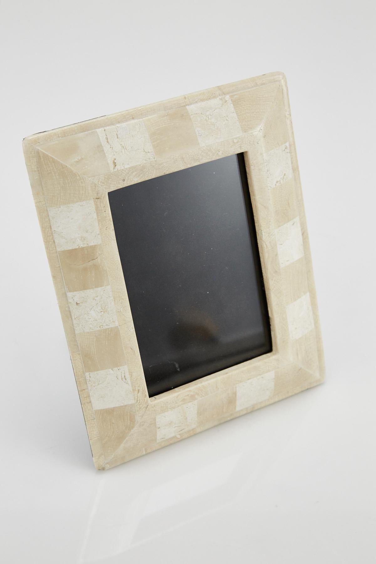 Rectangular picture frame in tessellated beige fossil stone with white stone squares surrounding the frame face. Black felt back. Opening for picture measures 6 1/2 x 4 1/2 in., frame overall measures 10 x 8 in.

All furnishings are made from 100%