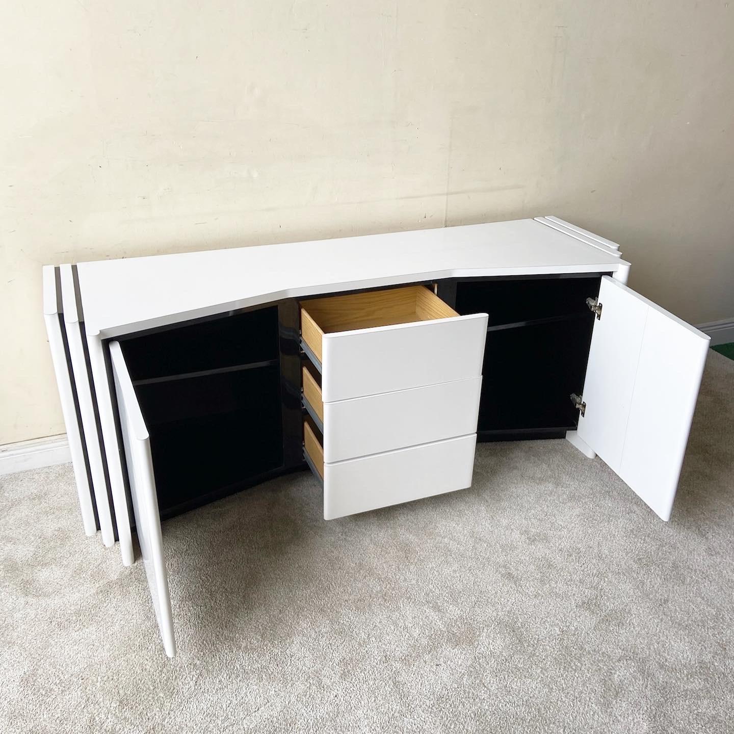 Amazing postmodern sculpted credenza. Features a white and black lacquer laminate with three central doors and cabinets with ample storage space.