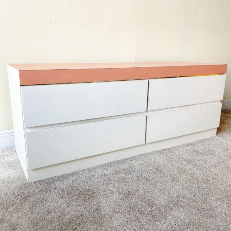 Incredible postmodern 6 drawer dresser. Pink Matte laminate top accentuates the white lacquer laminate body of the dresser.dazzling gold stripe borders the top drawer from the pink top.

Additional information:
Materials: Wood
Color: White
Style: