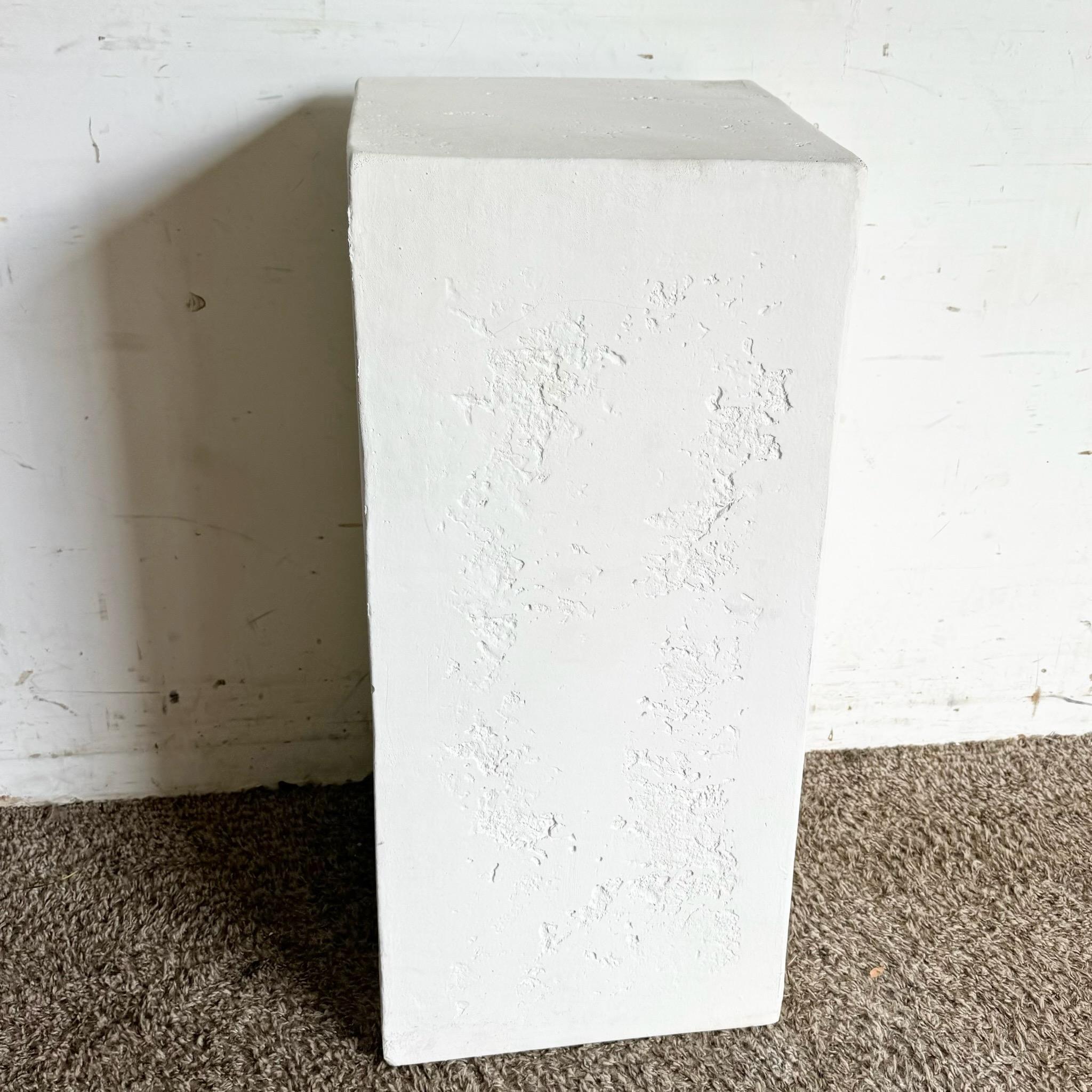 Ce piédestal postmoderne en plâtre blanc ajoute un élément sculptural à n'importe quelle pièce grâce à son design minimaliste et à sa finition texturée. Parfait pour exposer des œuvres d'art ou des plantes, il sert de pièce élégante et polyvalente