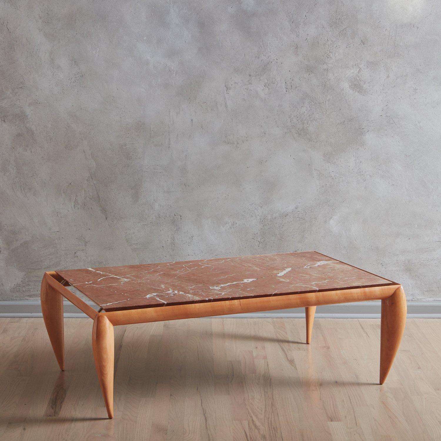 A postmodern coffee table featuring a lacquered wooden base with striking tapered, curved legs. This piece has a rectangular Rosso Alicante marble tabletop with gorgeous veining in coral, cream and red hues. The top sits on metal hardware, making it