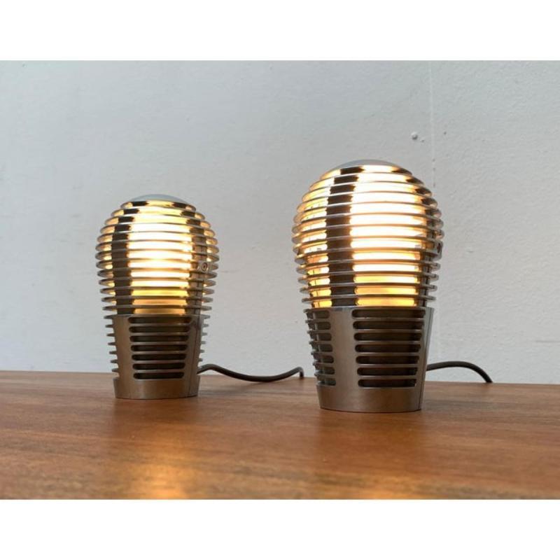Una rara lámpara de sobremesa del fabricante español Metalarte según un diseño de Sergio y Óscar Devesa de los años 80.

La forma de este diseño se basa en las propiedades y posibilidades del material utilizado. El aluminio fundido sólo permite esta