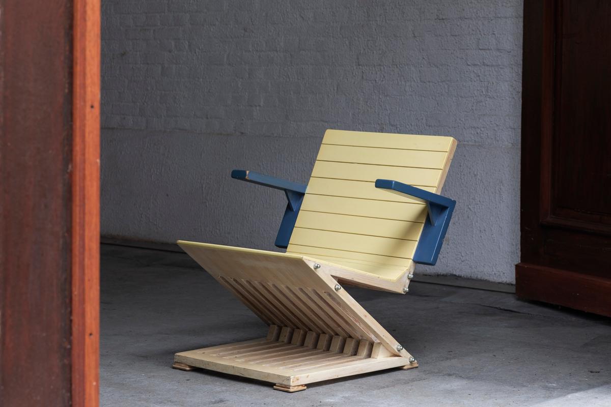 Postmoderner Beistellstuhl, inspiriert von dem berühmten Zick-Zack-Stuhl von Gerrit Rietveld. Dieser Stuhl aus Kiefernholz in Hellgelb und Blau kann mit seinen skulpturalen Formen und seiner fröhlichen Farbpalette jeden Raum aufhellen. Einige