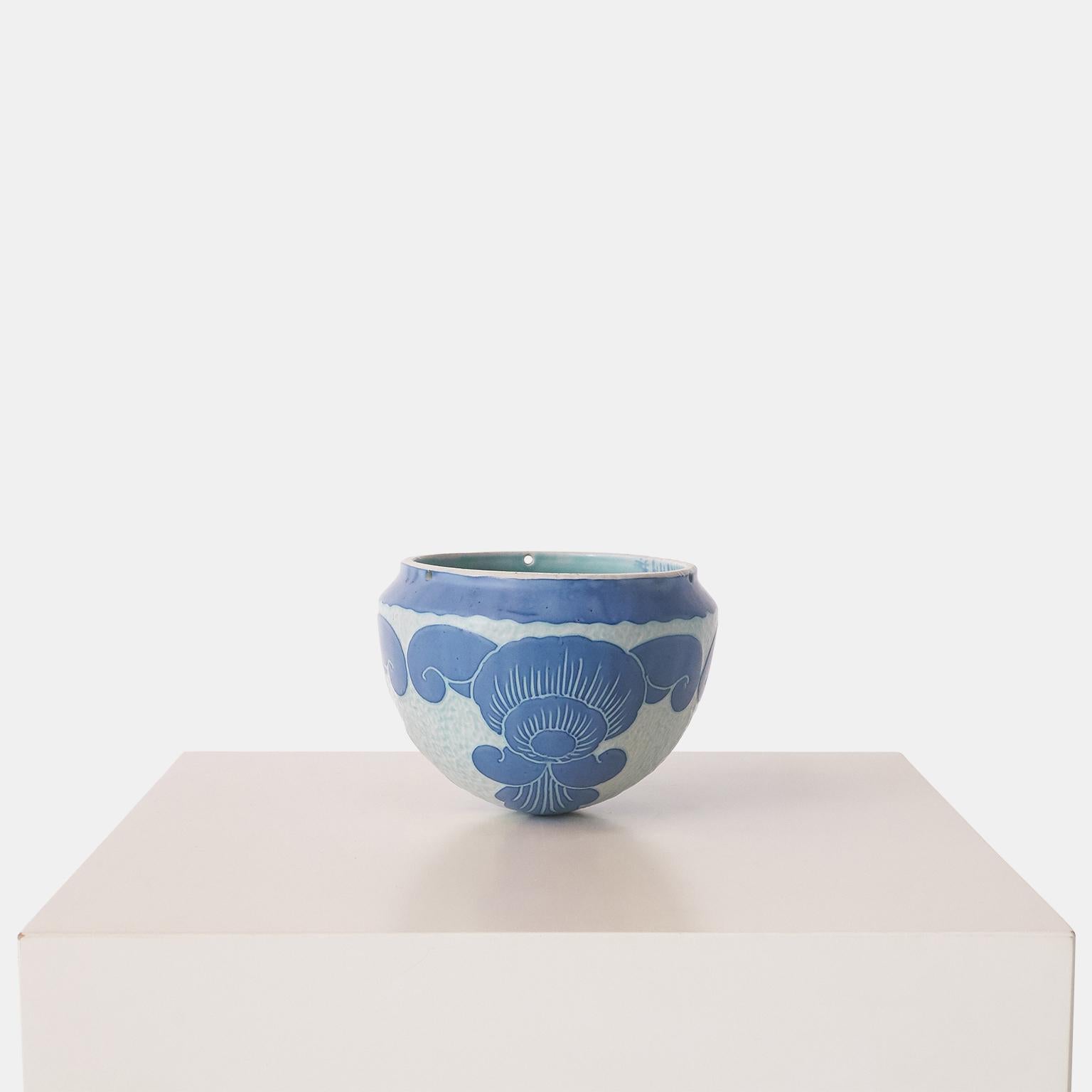 Vase bleu fait main par Josef Ekberg pour Gustavsberg. Chaque pièce est unique et décorée selon la technique du Sgrafitto, mise au point par Ekberg lui-même. Cette pièce comporte trois petits trous dans le bord supérieur et est conçue pour être