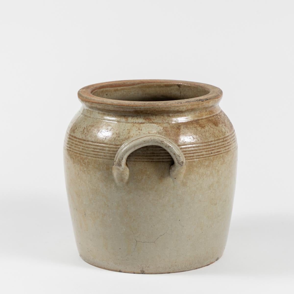 Late 19th-century English clay hard-soldered pot with a taupe semi-matte aged finish. Earthy and serene, the vessel features a thin rounded lip and raised handles on either side, and could work as both decorative and functional object. 

England,