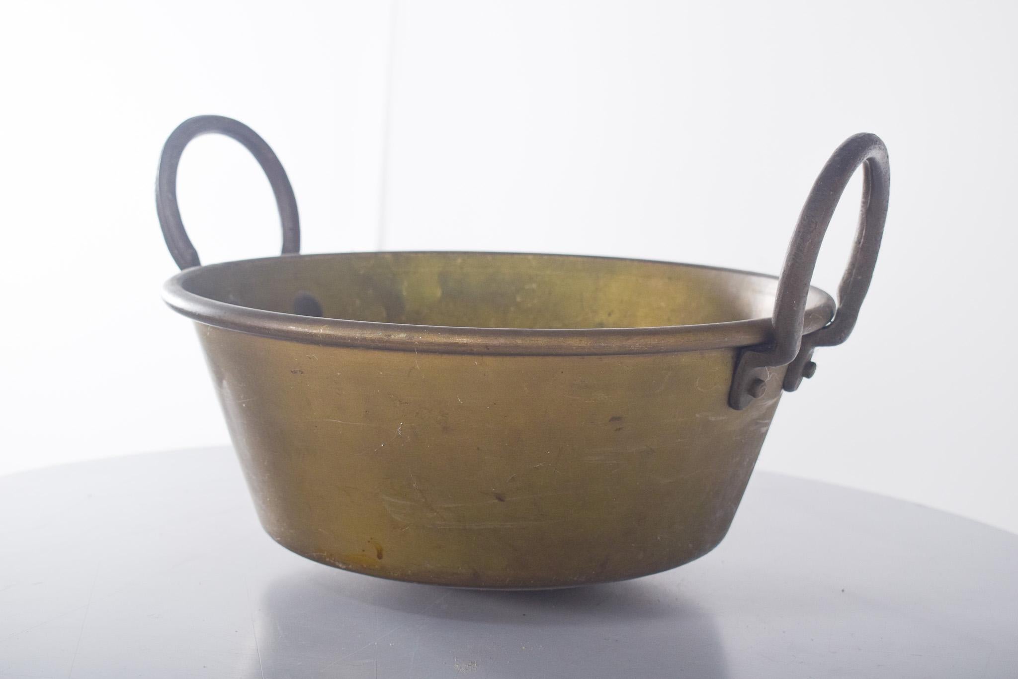 Topf mit zwei Griffen, aus Messing. Breit und tief, mit zwei seitlichen Griffen, die durch Metallnieten zusammengehalten werden. Das Stück weist eine für die Zeit charakteristische Patina auf, die ihm einen rustikalen Charme verleiht und seine