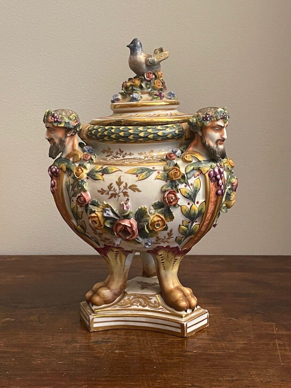 Potiche in ceramic, 19th century
Elegant vase in ceramic with a triangular base, faceted, richly decorated with floral motifs, and depicting Bacchus crowned by grapes at the three corners, the lid is decorated with a small handle in the shape of a