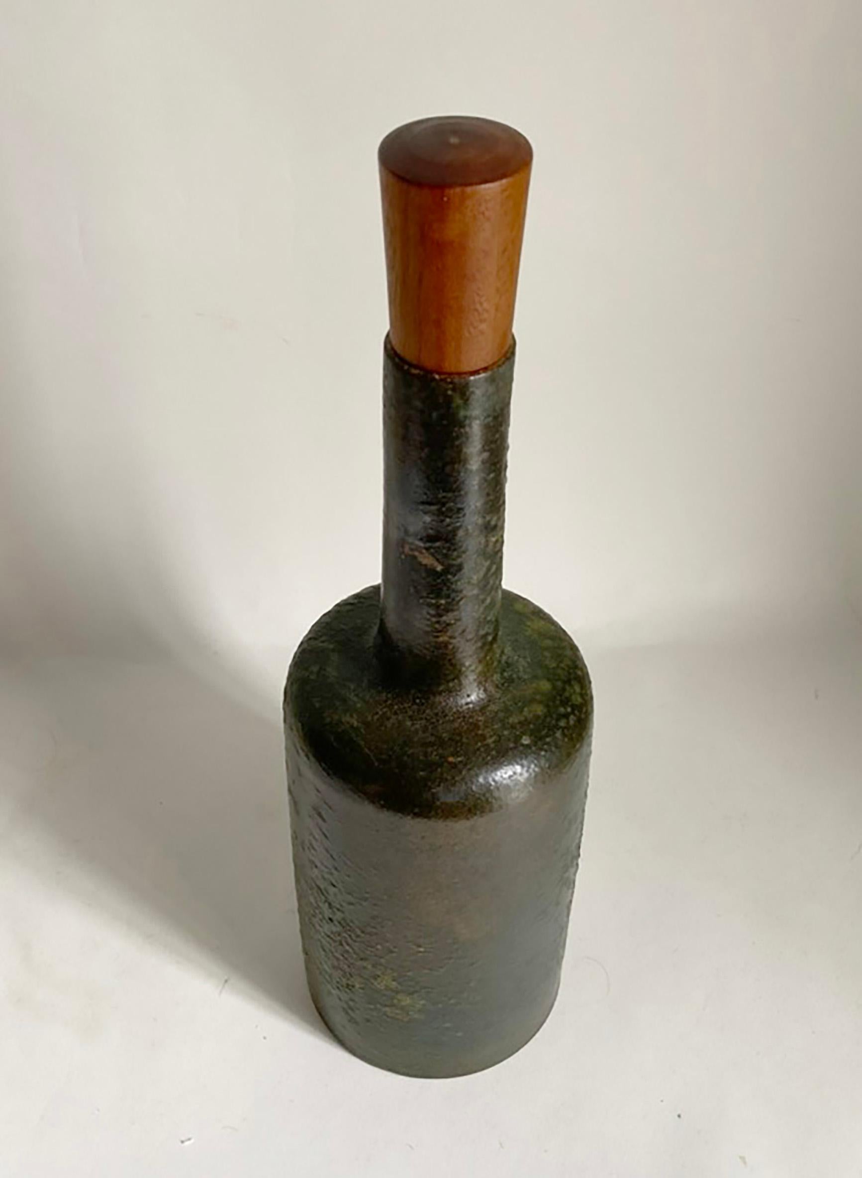Here is a very handsome stopped Italian bottle or decanter in a rich, dark green textured glaze. We are quite sure this is Aldo Londi design for Bitossi. The piece retains its original wood stopper. The bottle and stopper are in very good condition