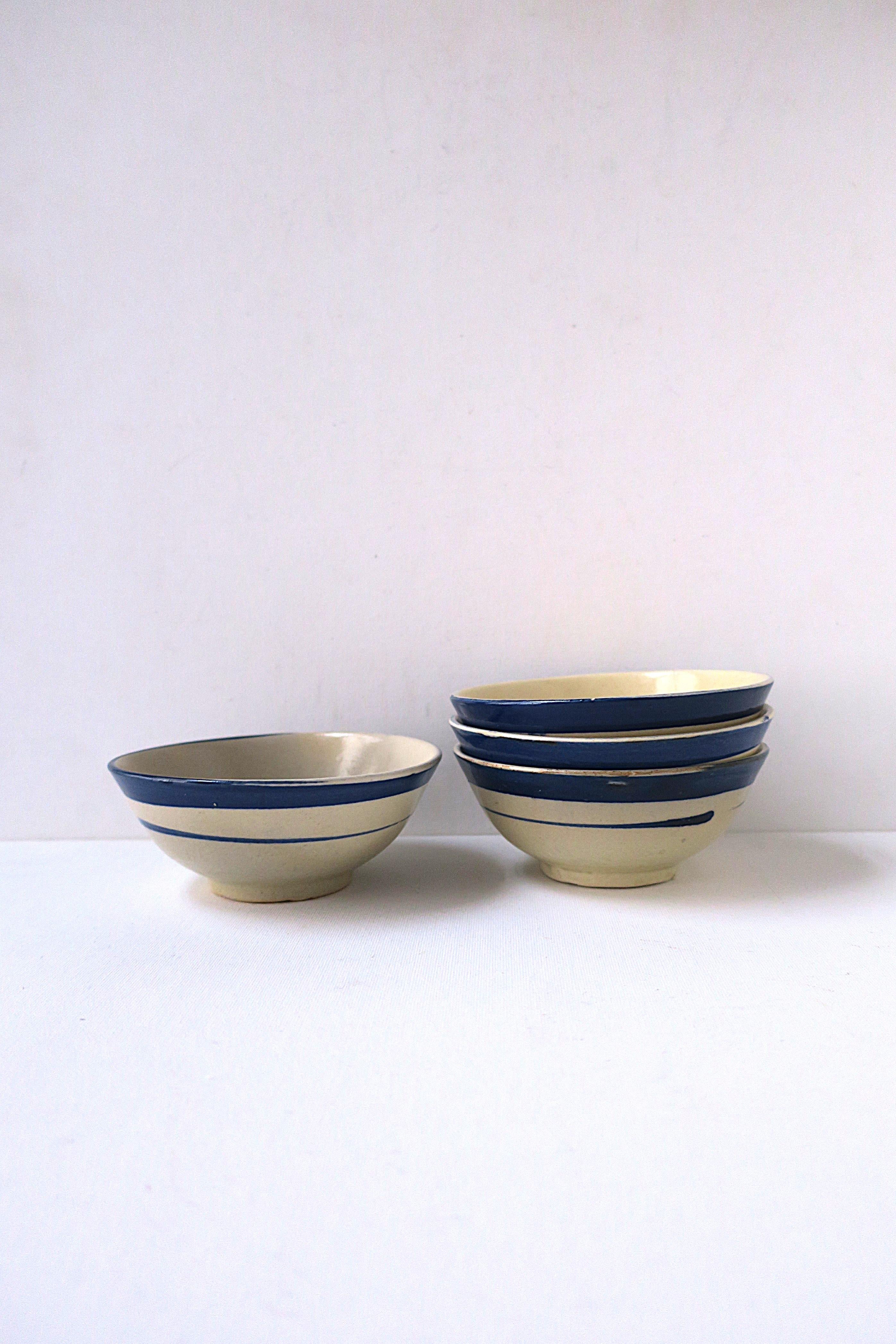 A set of four (4) hand-made small serving pottery bowls, in the Country design style, circa late-20th century. Bowls are an off-white stone hue with a navy-blue accent stripe around, glazed. Use for sauces, dipping, berries, etc., many uses. 