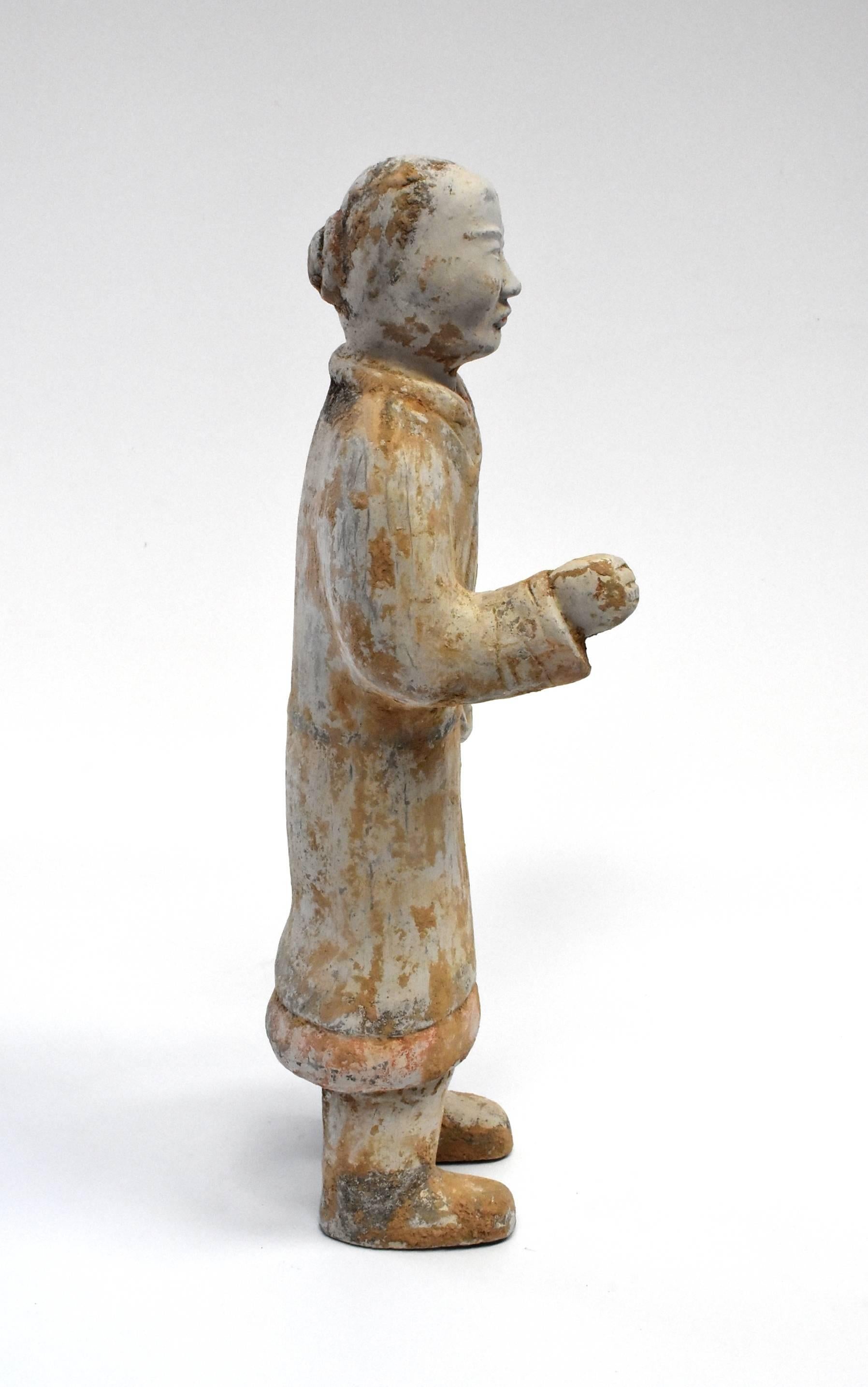 A fantastic Han style terracotta figure. Such a figure is seen in the Han dynasty dating 206 BC-220 AD. The figure appears to be a servant or a hostler. His hair is in a bun and wears layers of wrap robes, all consistent with the Han era's style. A