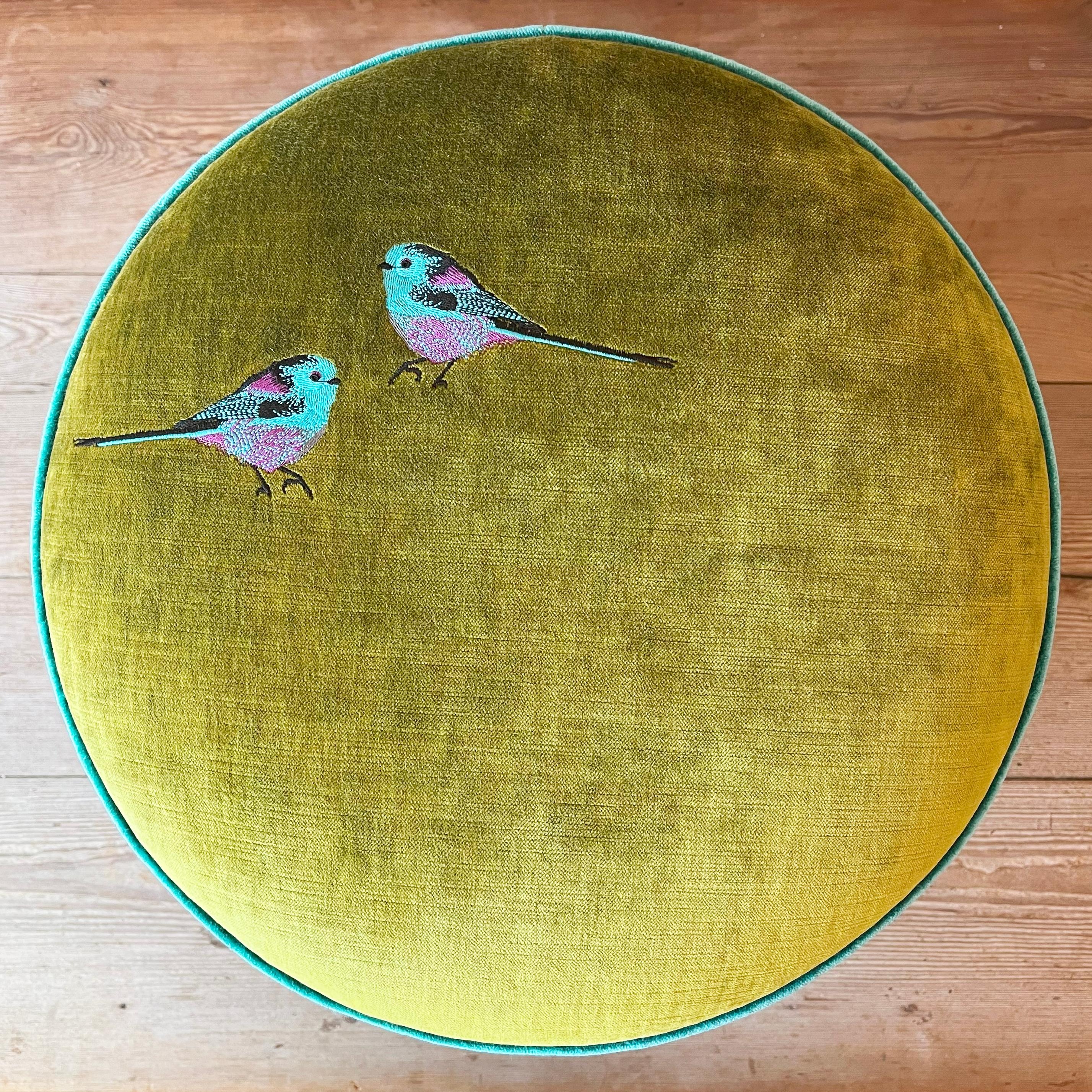 Un pouf come un piccolo gioiello domestico: verde, viola e un accento di azzurro si intrecciano in una palette all’insegna dell’eleganza e dell’artigianalità, impreziosita da un minuzioso ricamo manuale di due pettirossi colorati.
Il design è