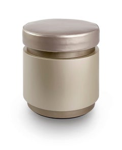 Puf en acabado ébano pulido Tapa de tela y bordes decorativos de metal líquido