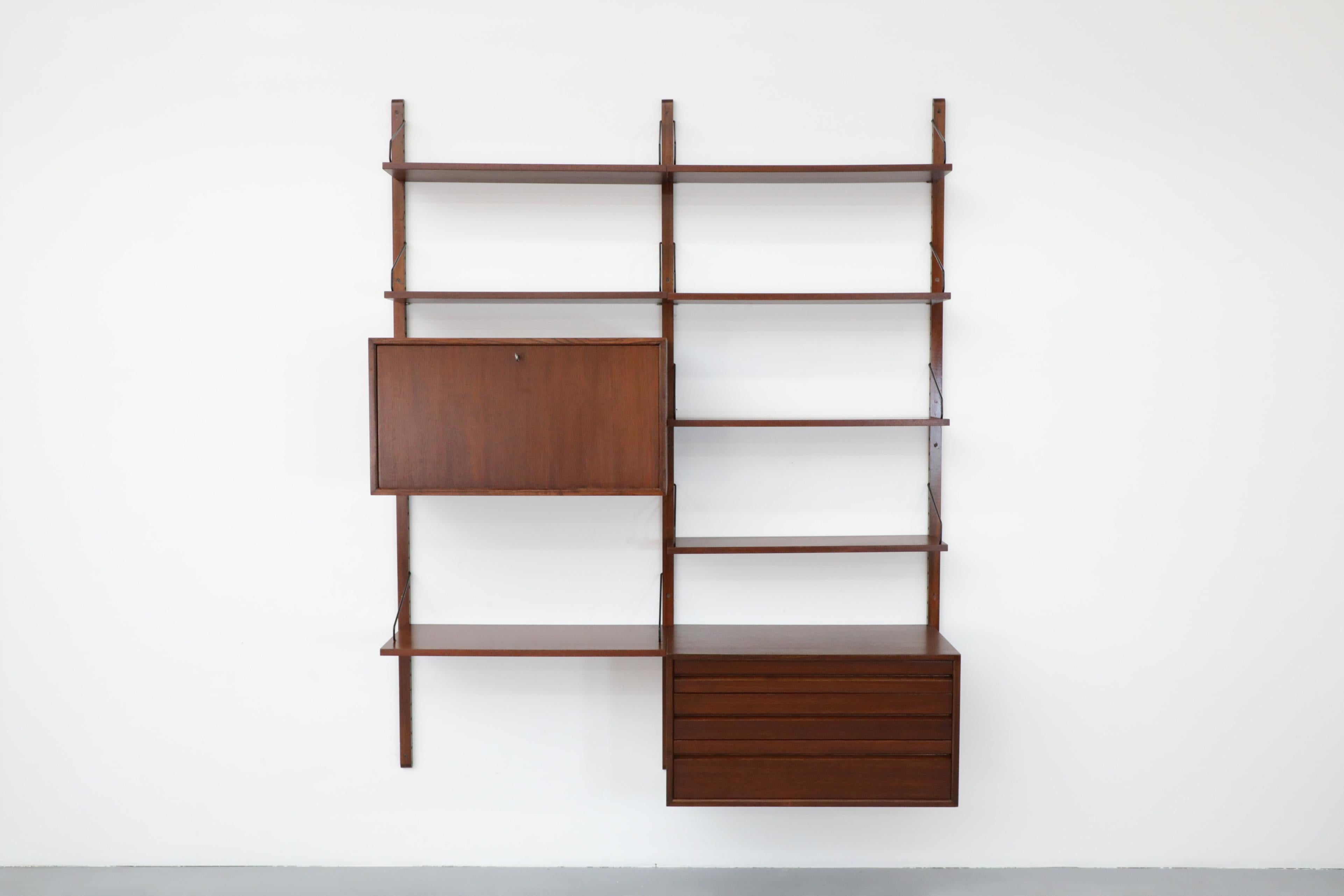 Two section interchangeable wall mounted Royal System with rosewood shelving, a drop down bar or desk cabinet and a drawer cabinet by Poul Cadovius. The unit has six small shelves (8inch deep), one larger desk shelf (12inch deep) and two cabinets