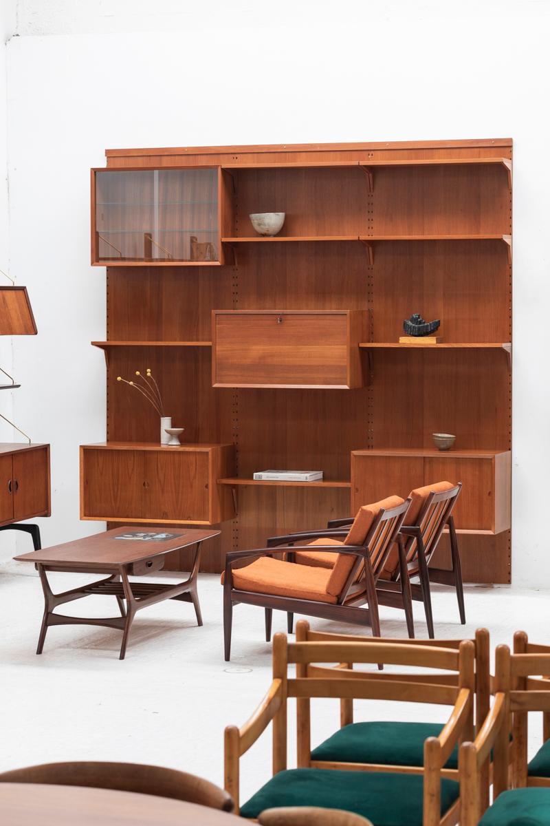 Three-column wall unit designed by Poul Cadovius and produced by Cado in Denmark around 1960. This shelving system with teak backplates is part of the luxurious Cado series, with wooden dowel supports. It features a bar cabinet with mirror inside, 2